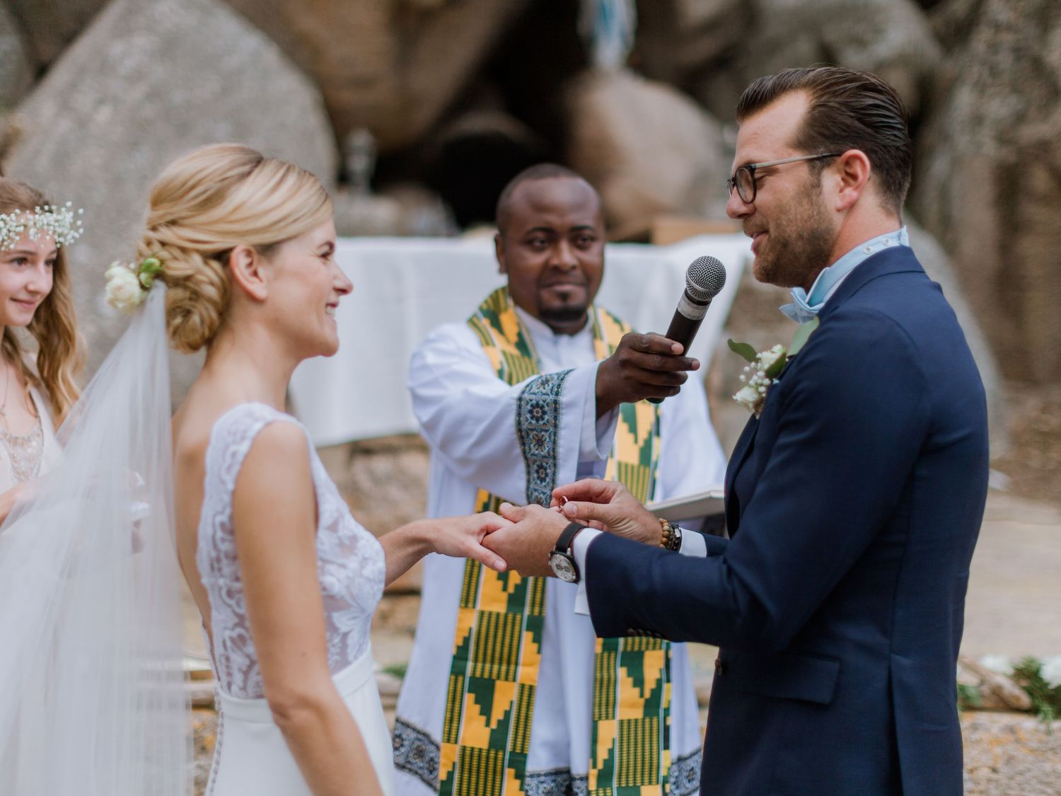 Les mariés échangent leurs vœux lors d'une cérémonie de mariage en plein air, l'officiant tenant le micro.