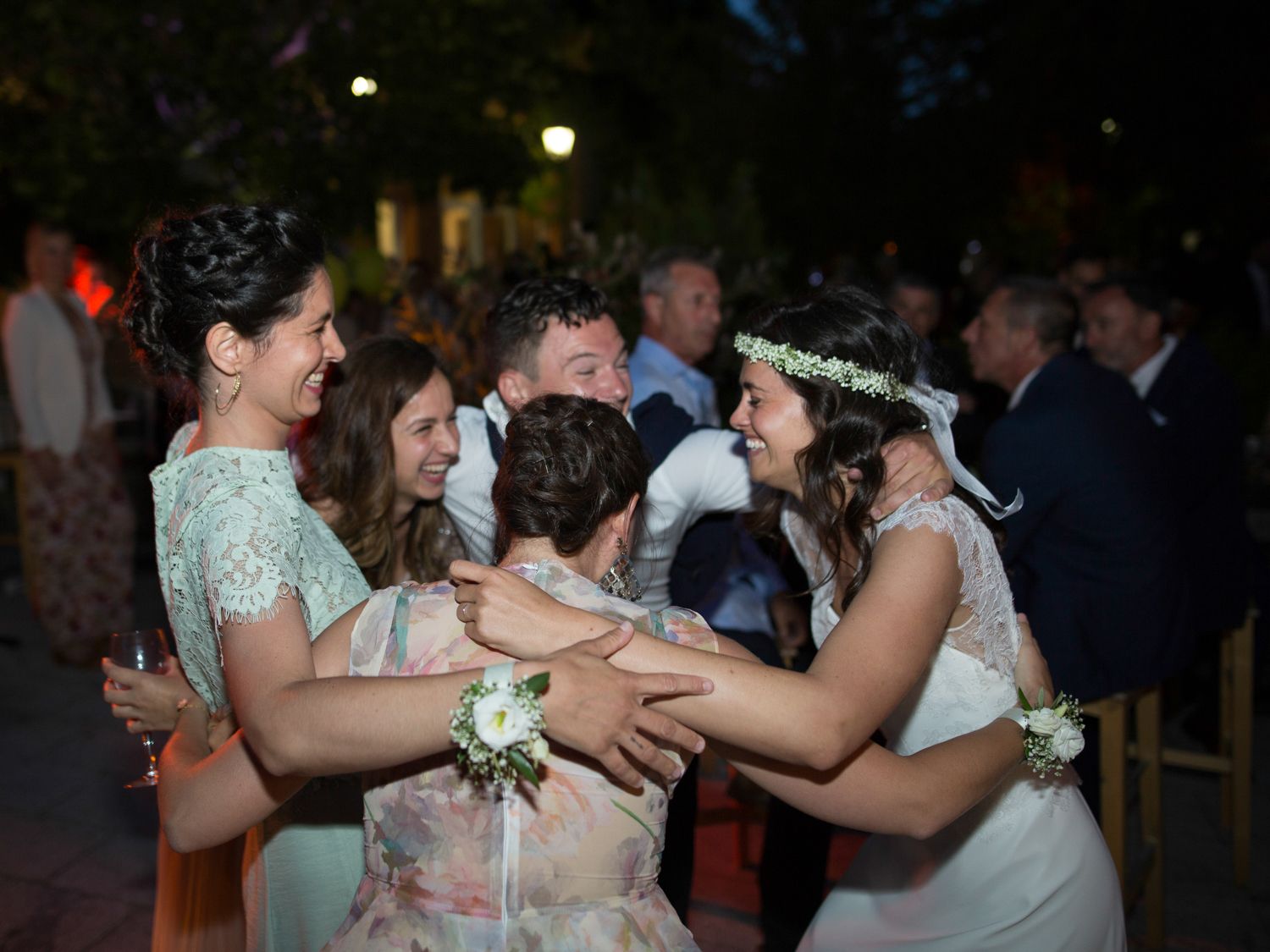 Célébration de mariage joyeuse avec les demoiselles d'honneur et la mariée dansant en plein air la nuit, portant des accessoires floraux.