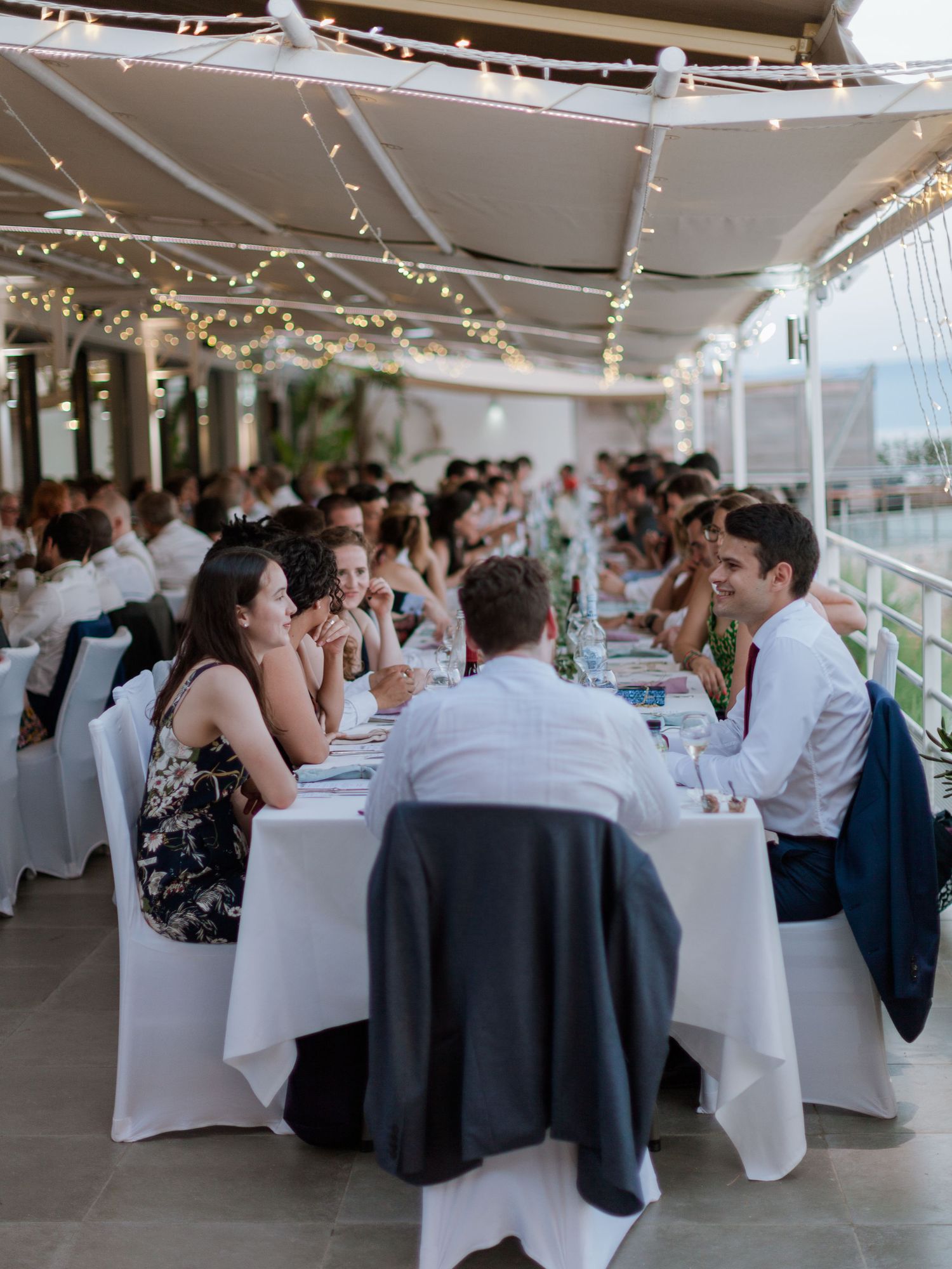 Des invités assis à de longues tables recouvertes de nappes blanches lors d'une élégante réception de mariage a l'hotel week end ajaccio