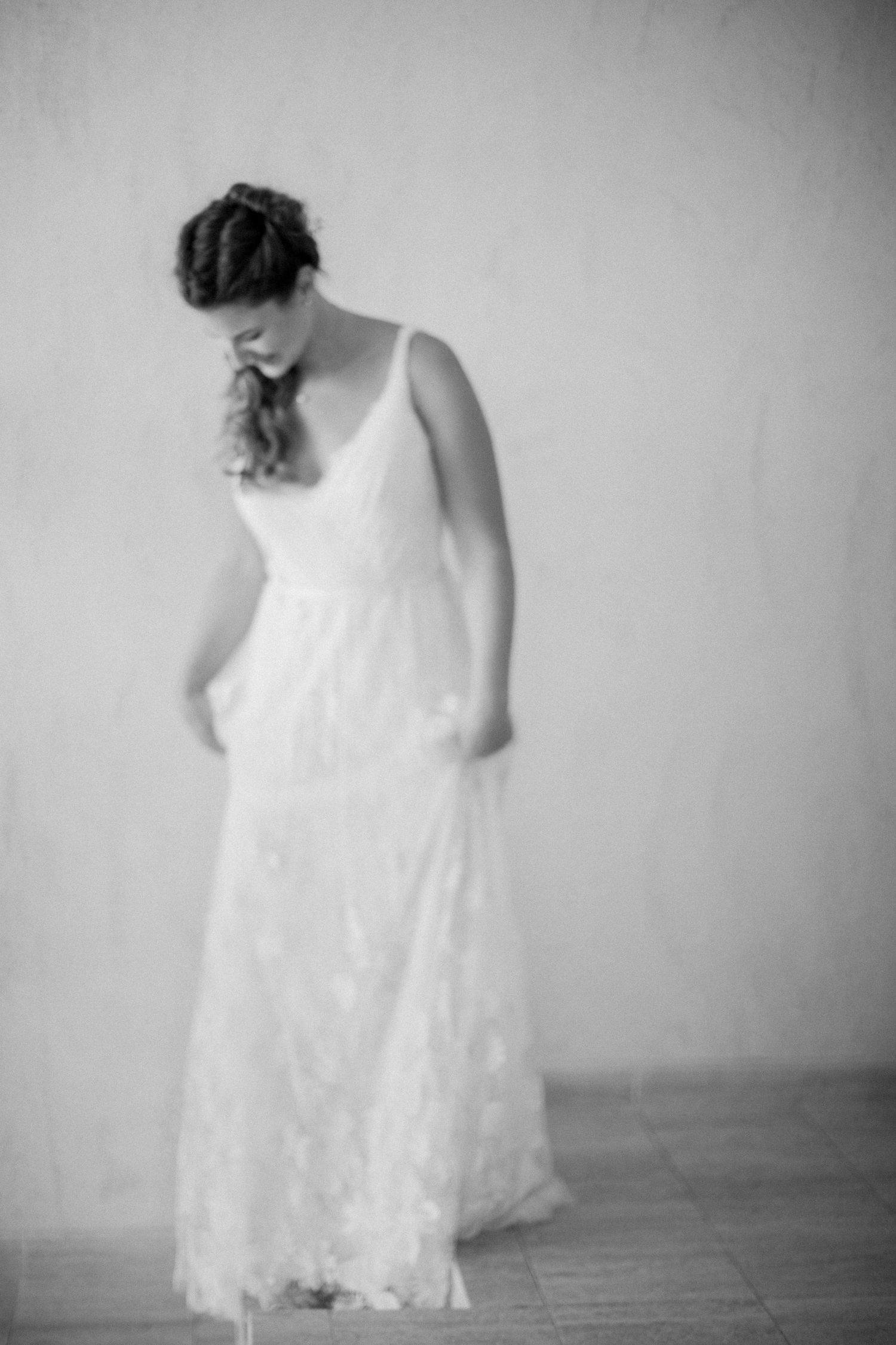 Portrait de mariage en noir et blanc d'une mariée en élégante robe en dentelle, le regard baissé.