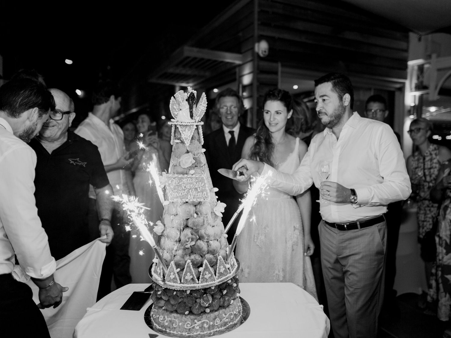 Les mariés coupent une pièce montée entourés de leurs invités, avec des cierges magiques, lors de la fête nocturne.
