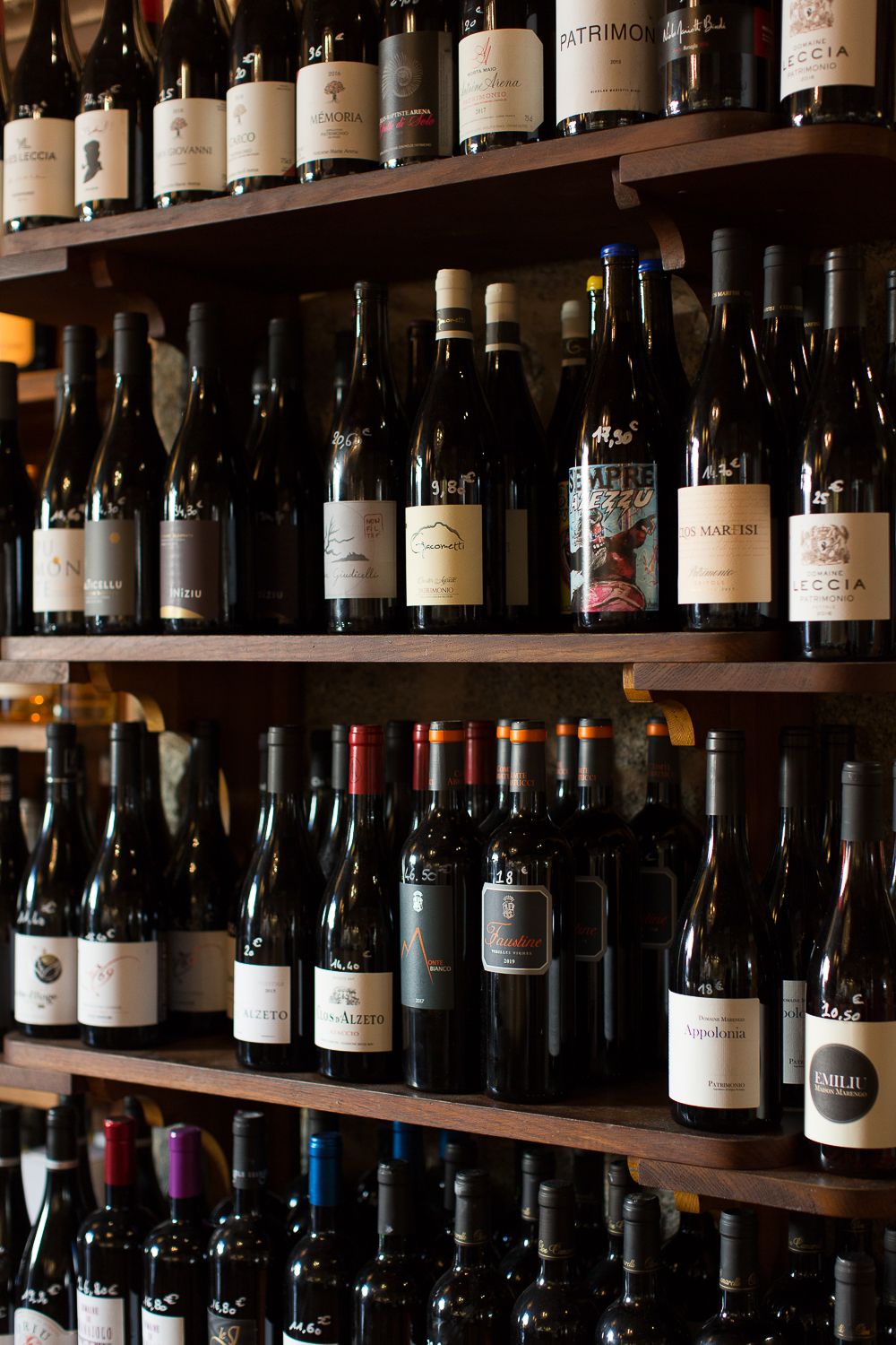 Vaste collection de bouteilles de vin exposée sur des étagères en bois sombre dans la cave à vin d'un restaurant haut de gamme.
