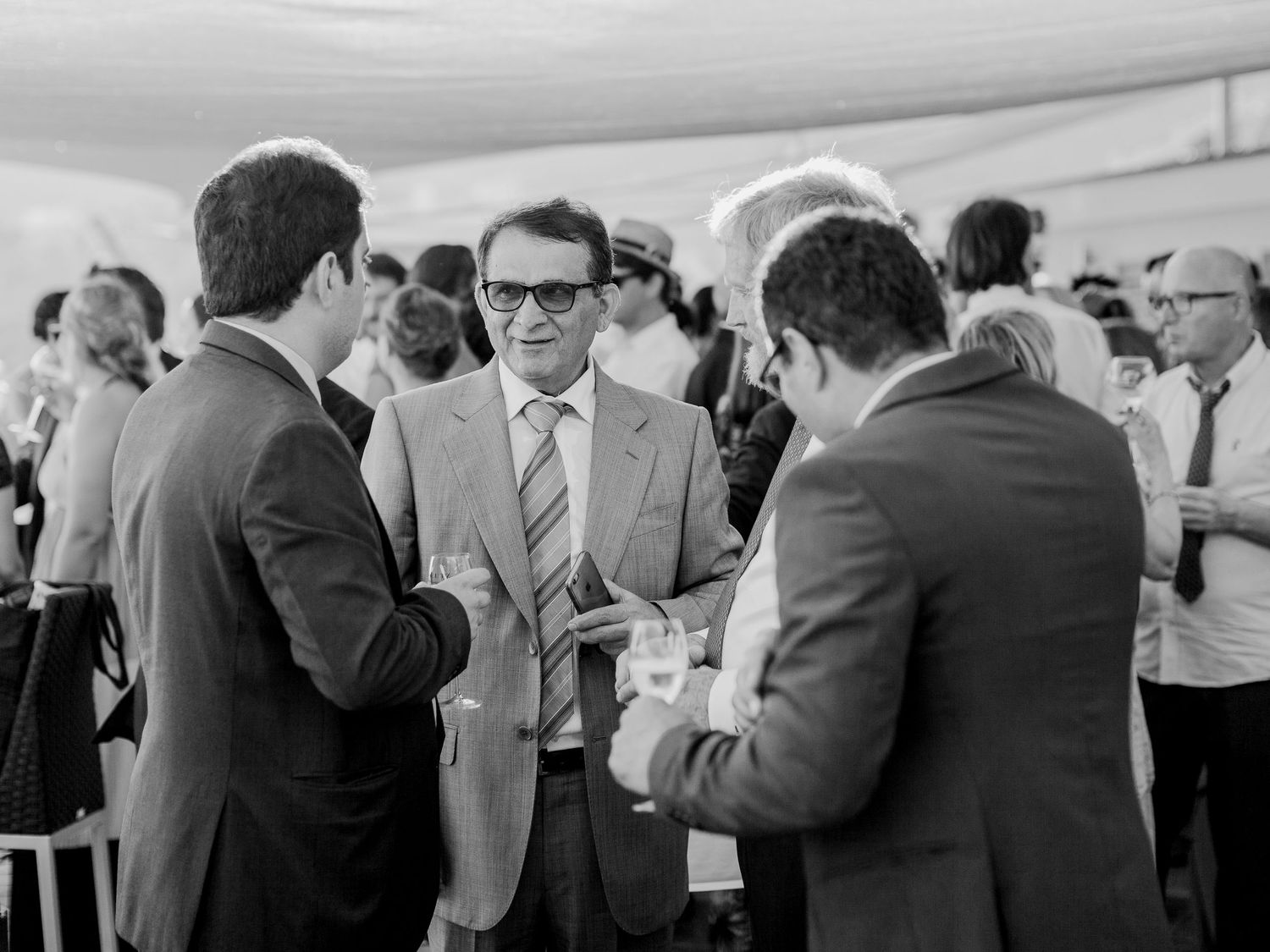 Photo en noir et blanc d'hommes d'affaires réseautant lors d'un événement officiel en plein air, en pleine conversation