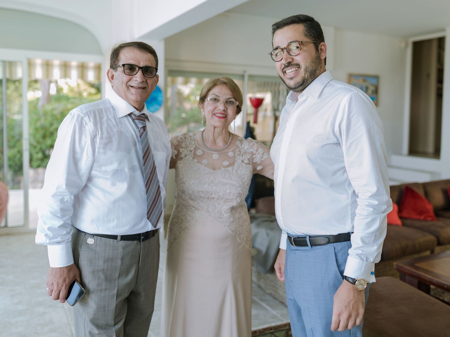 Trois personnes souriantes posant ensemble à l'intérieur lors d'une réception officielle : deux hommes et une femme en tenue élégante.