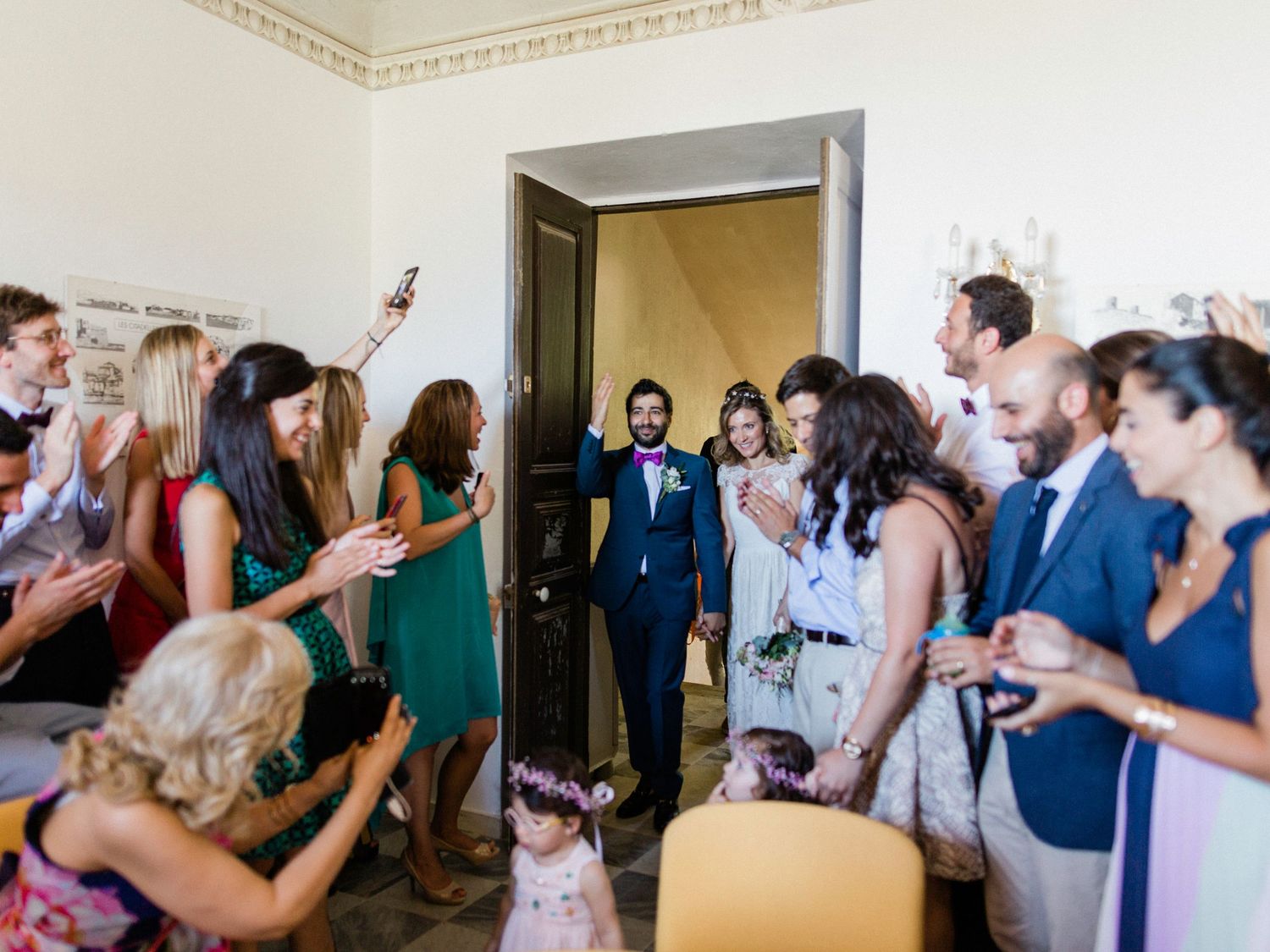 Wedding couple enters reception hall greeted by applauding guests in elegant venue.