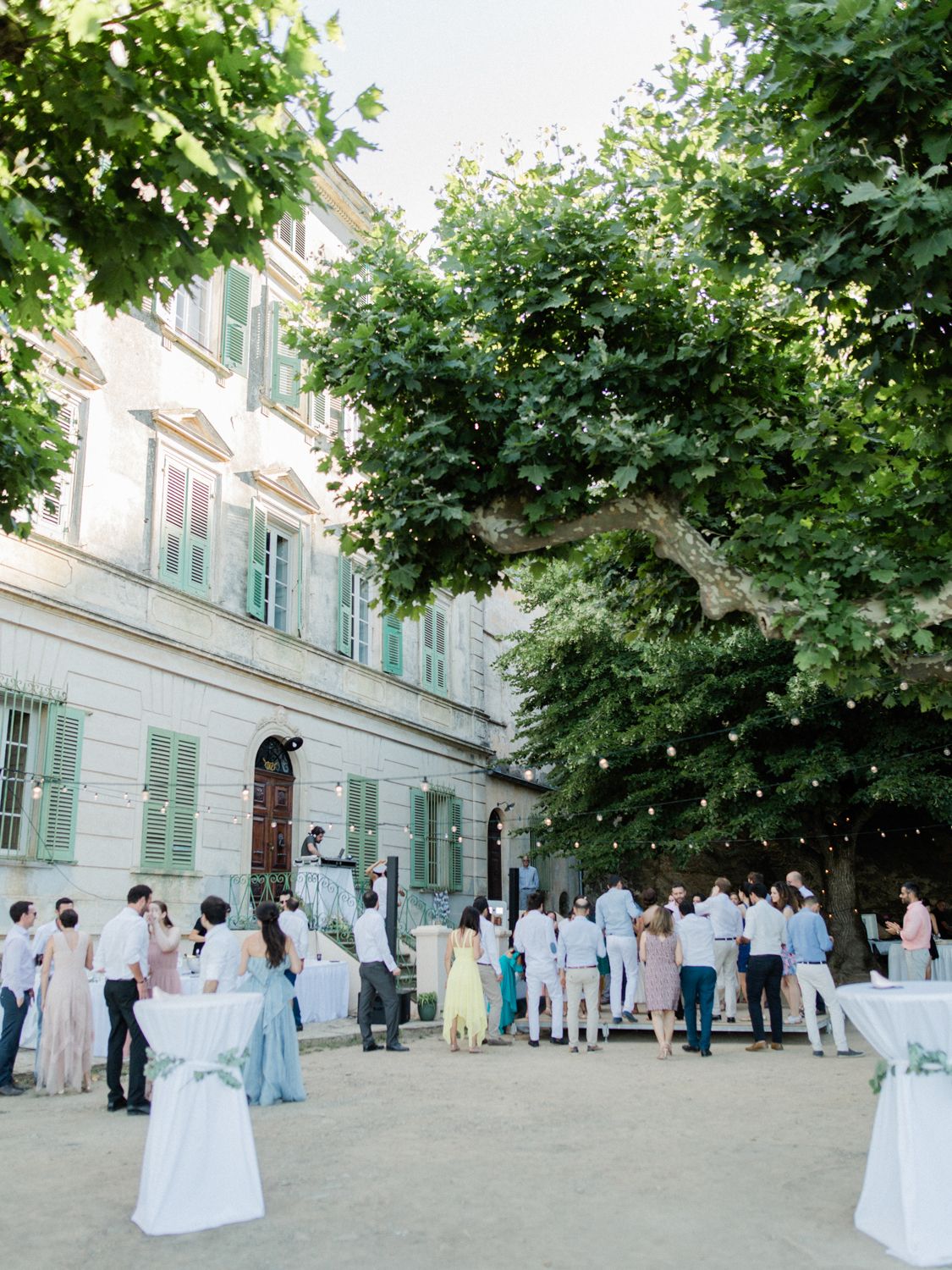 Élégant cocktail de mariage en plein air au Palazzu Nicrosi avec des volets verts et un grand arbre. Dans le cap Corse.