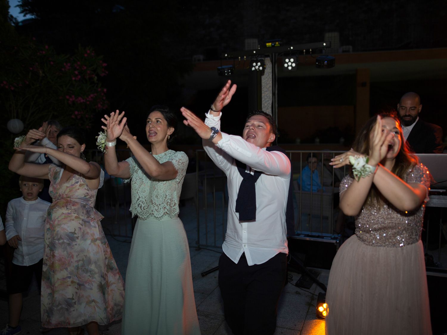 Des invités en tenue de soirée dansent joyeusement lors d'une réception de mariage en plein air.