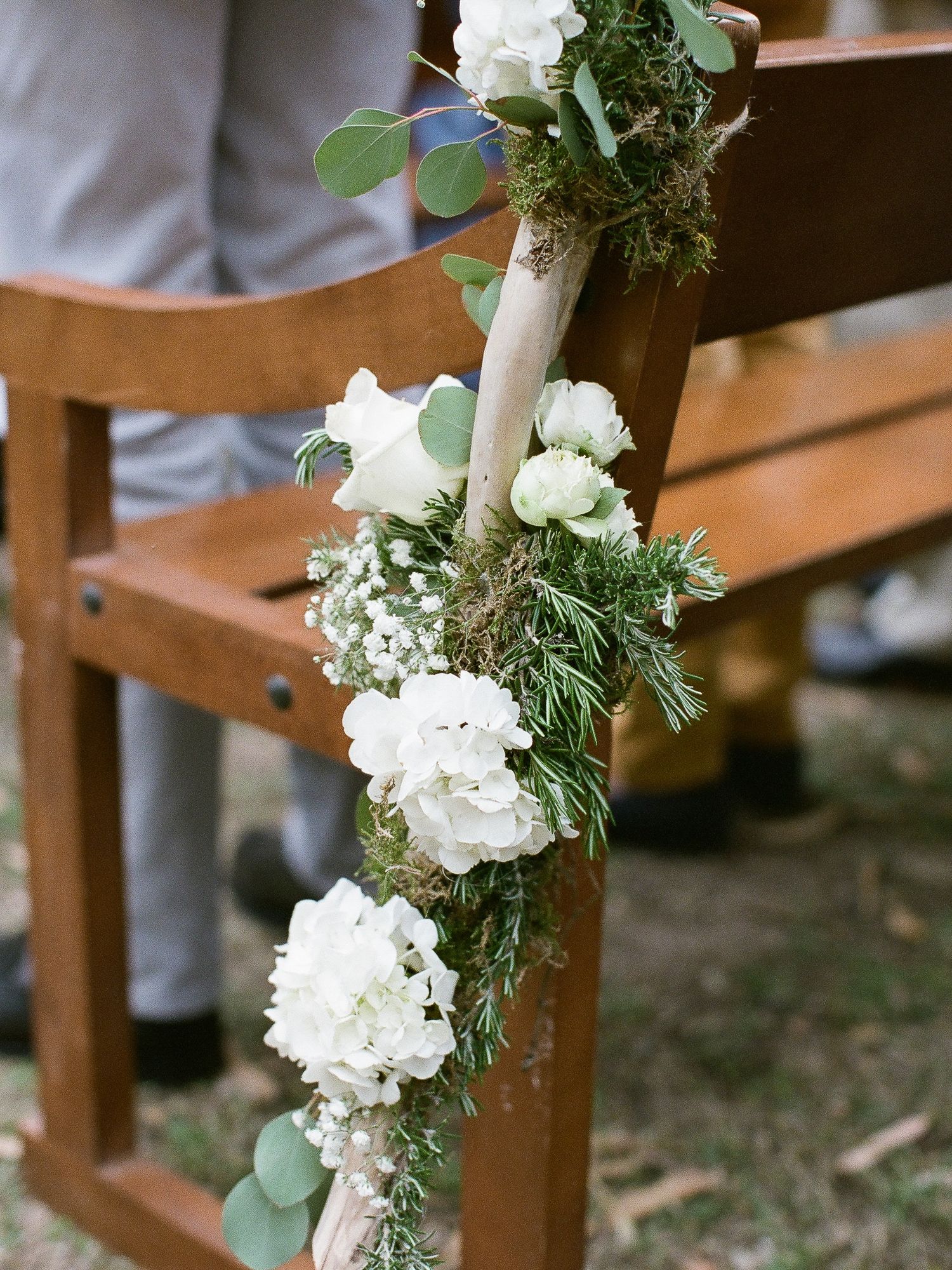 Composition florale d'hortensias blancs et de verdure sur une chaise en bois pour la décoration de l'allée lors d'une cérémonie de mariage.