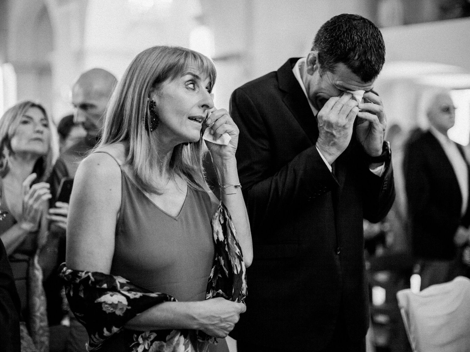 Emotional guests crying at a wedding ceremony in black and white photography.
