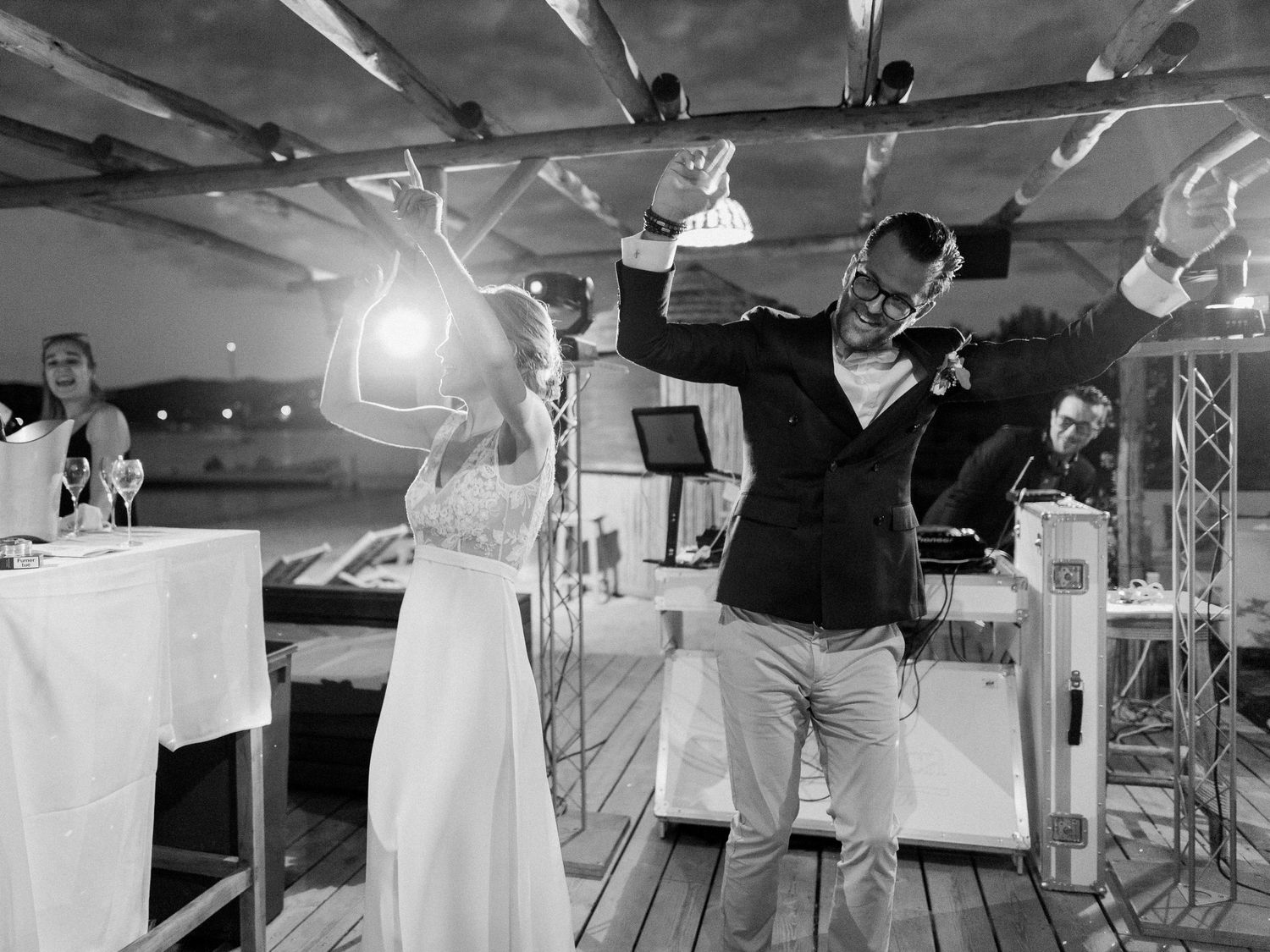 Photo en noir et blanc d'une mariée et d'un marié célébrant joyeusement sur une terrasse décorée pour leur réception de mariage en extérieur