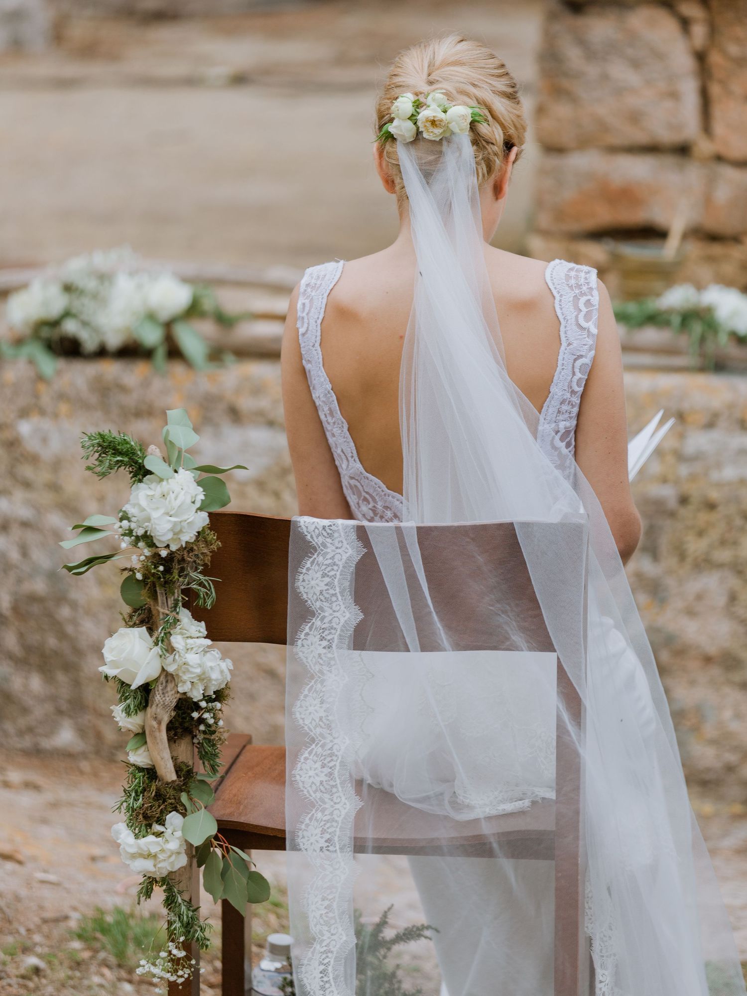 La mariée, vêtue d'une robe de mariée en dentelle et d'un voile fleuri, lors d'un mariage en corse à la trinité de Bonifacio