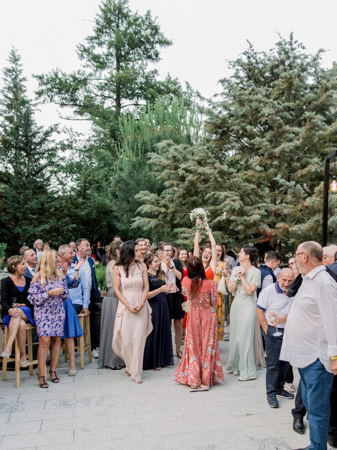 Moment de lancer de bouquet en plein air lors d'une cérémonie de mariage, les invités étant réunis sur une terrasse à Corte
