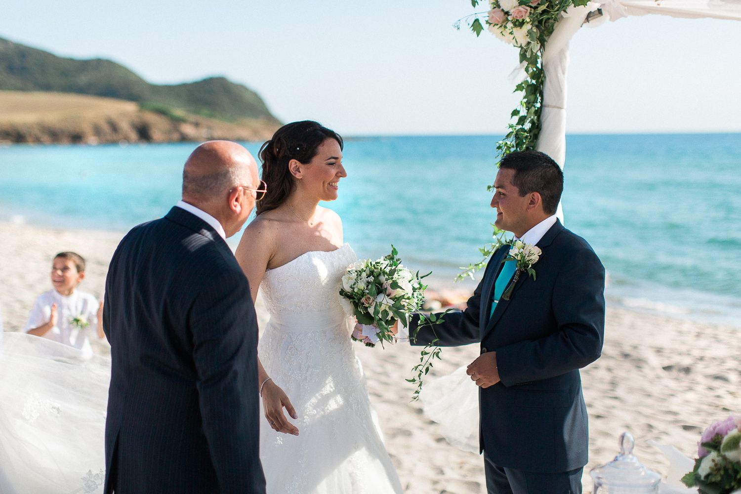 Les mariés échangent leurs vœux lors d'une magnifique cérémonie de mariage sur la plage, avec la mer turquoise en toile de fond en Corse.