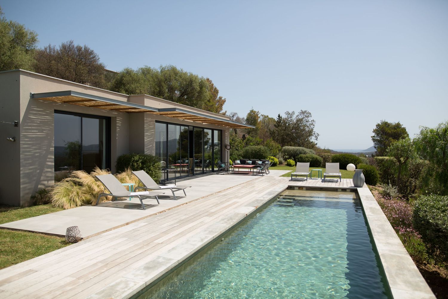 Villa moderne de luxe avec une longue piscine, une terrasse en bois et une vue imprenable sur les collines environnantes à Porto-Vecchio.