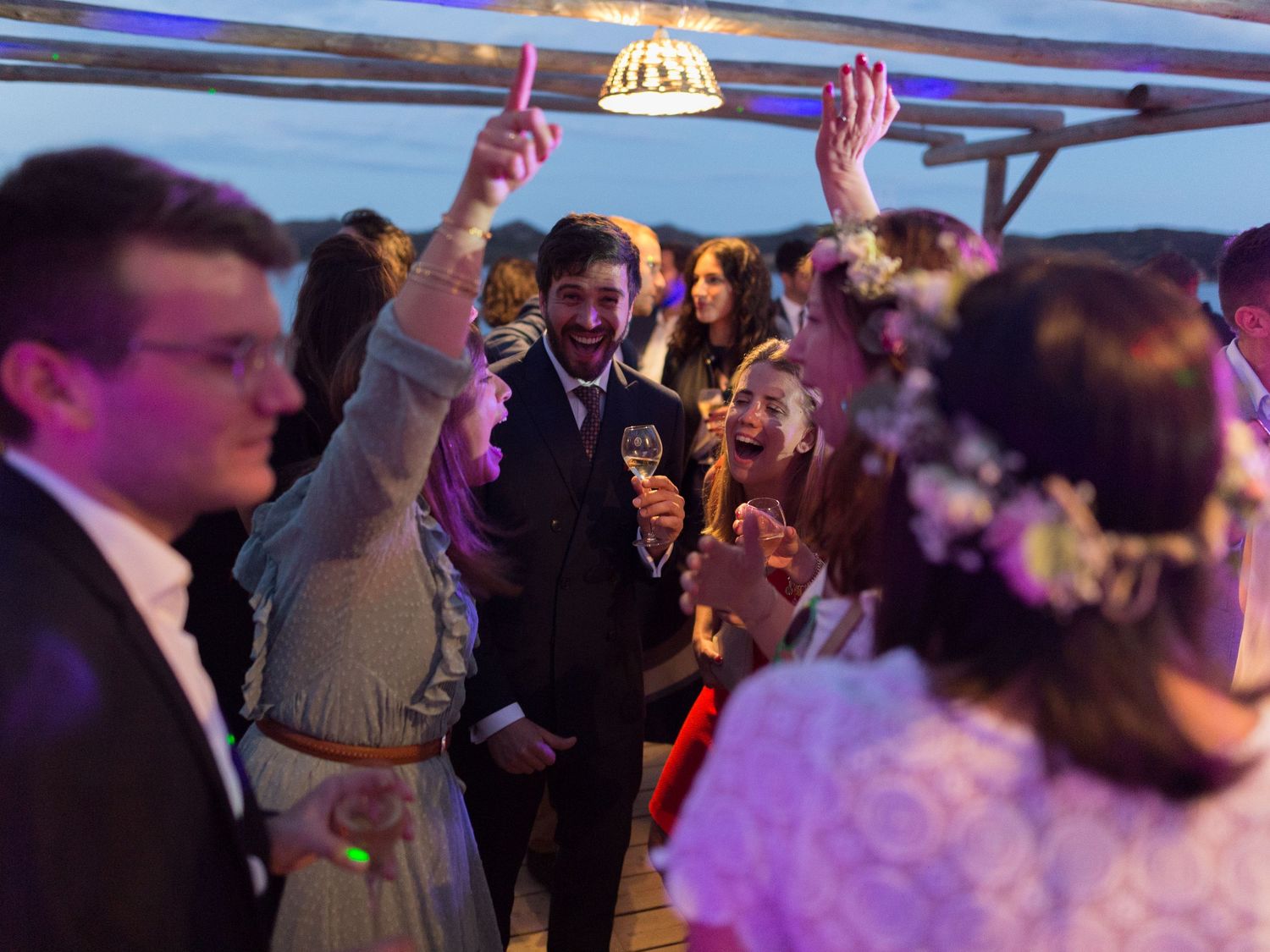 Réception de mariage joyeuse avec les mariés et leurs invités célébrant sur une terrasse sur le toit en soirée.