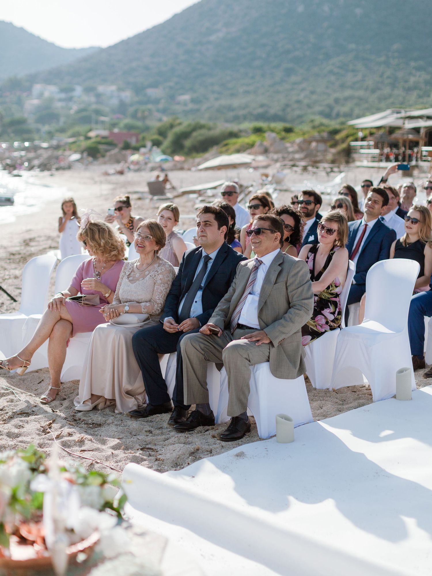 Des invités assis sur des chaises blanches lors d'une cérémonie de mariage sur la plage, à l'hôtel le week end à Ajaccio