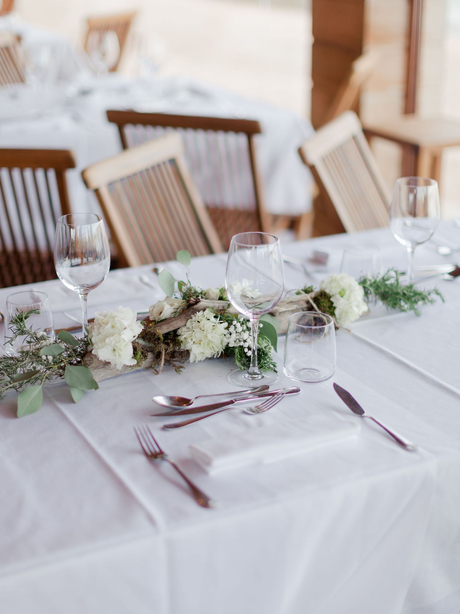 Élégante table de mariage dressée avec des hortensias blancs, un centre de table végétal, des verres en cristal et des couverts en or