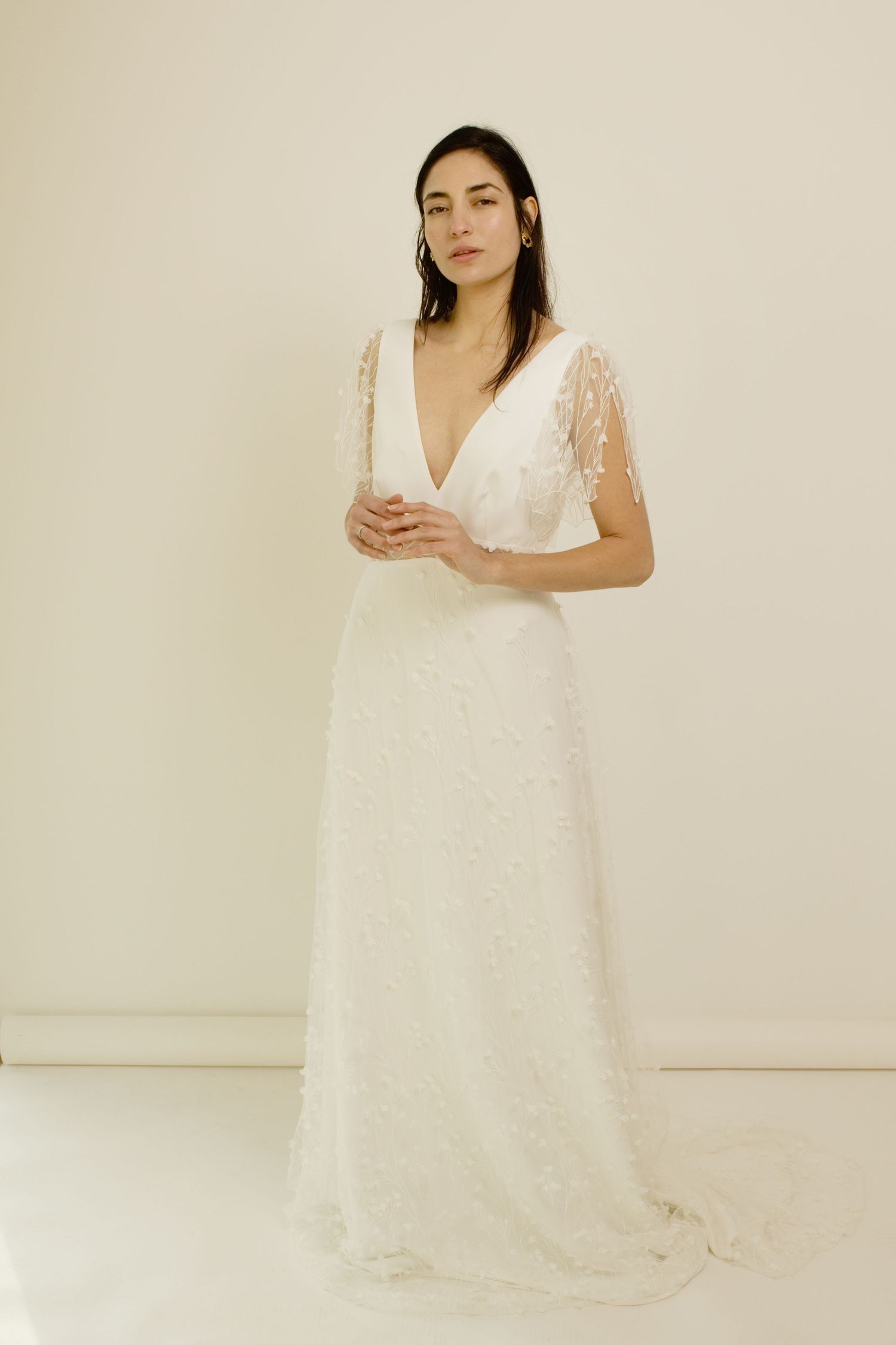 Robe de mariée élégante en dentelle blanche, dotée d'un décolleté en V profond et de manches volantées, portée par un mannequin en studio