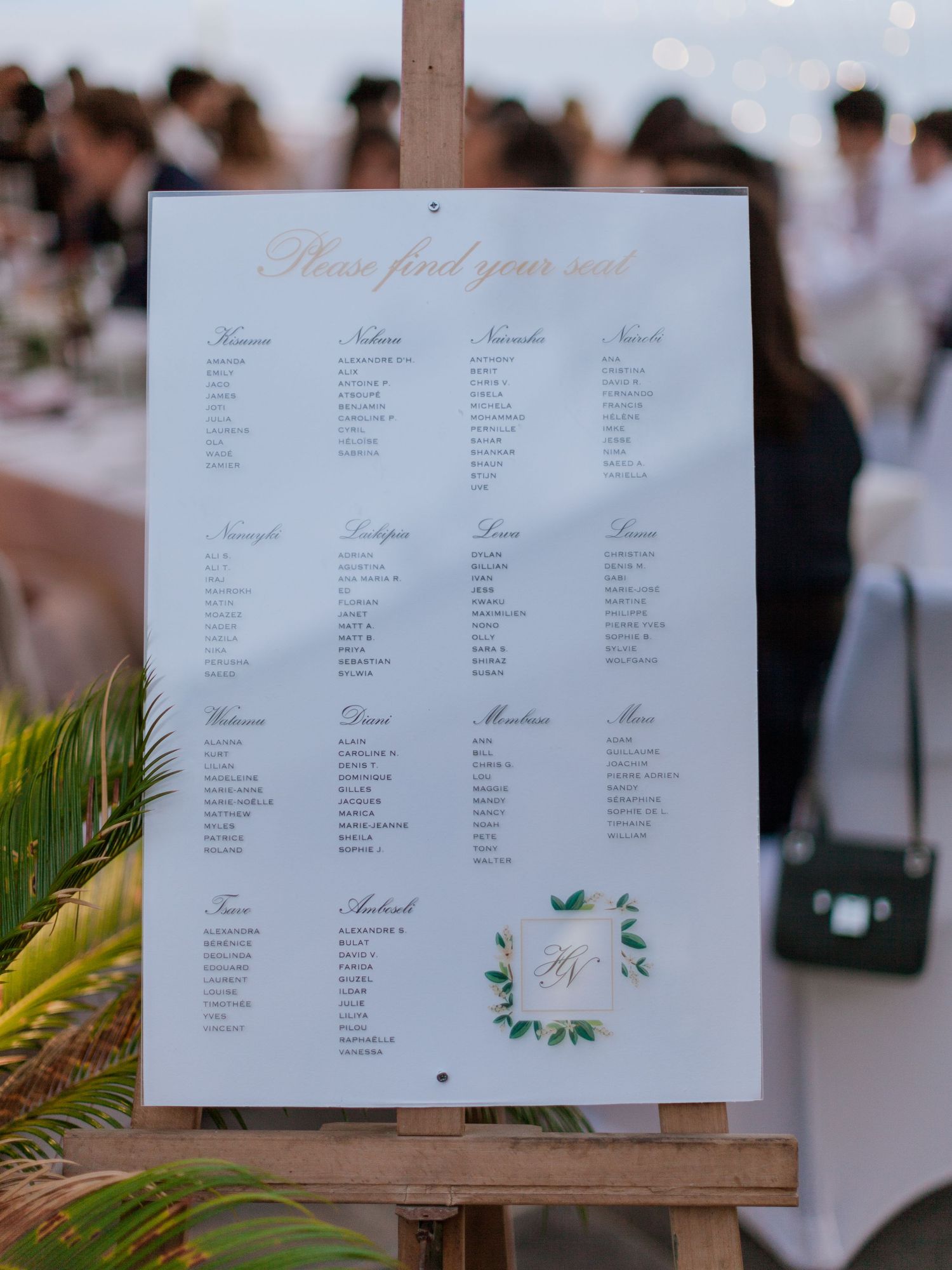 Élégant plan de table de mariage sur chevalet, avec en-tête en écriture manuscrite dorée, monogramme agrémenté de feuillage