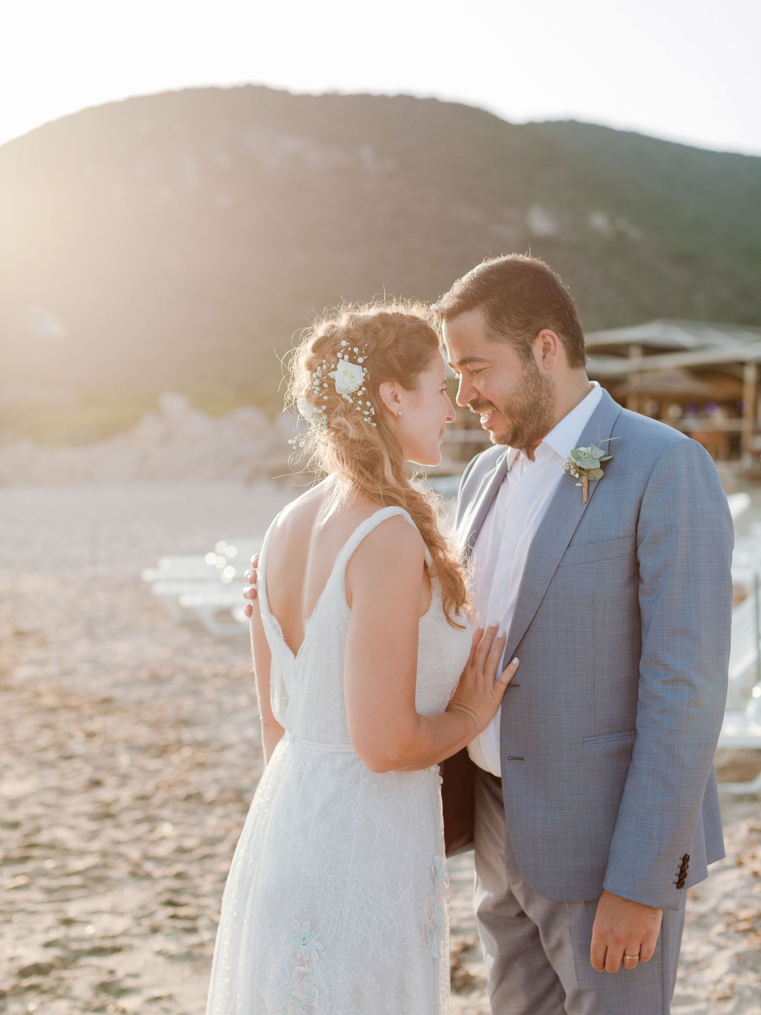 Les mariés partagent un moment intime sur une plage au coucher du soleil, se souriant tendrement sur la plage à Ajaccio