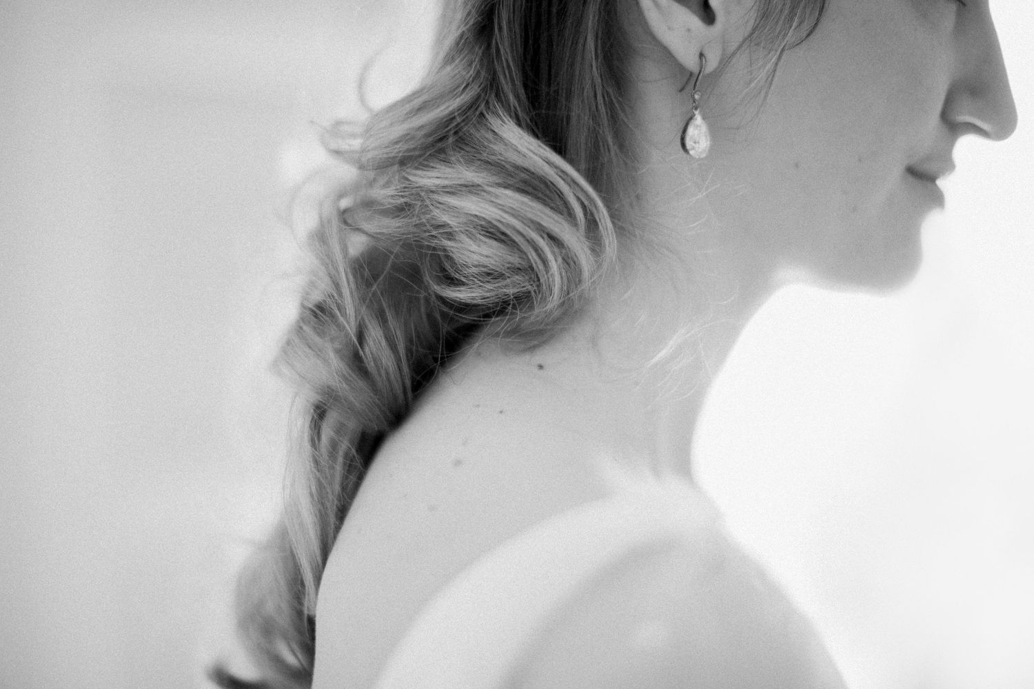Portrait de mariée en noir et blanc mettant en valeur d'élégantes boucles d'oreilles en perles et un profil de cou gracieux.