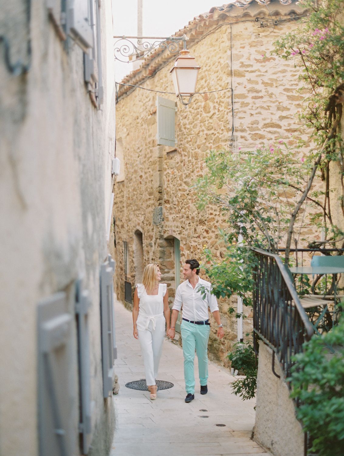 Un couple se promène main dans la main dans une charmante ruelle pavée d'un village européen pittoresque.