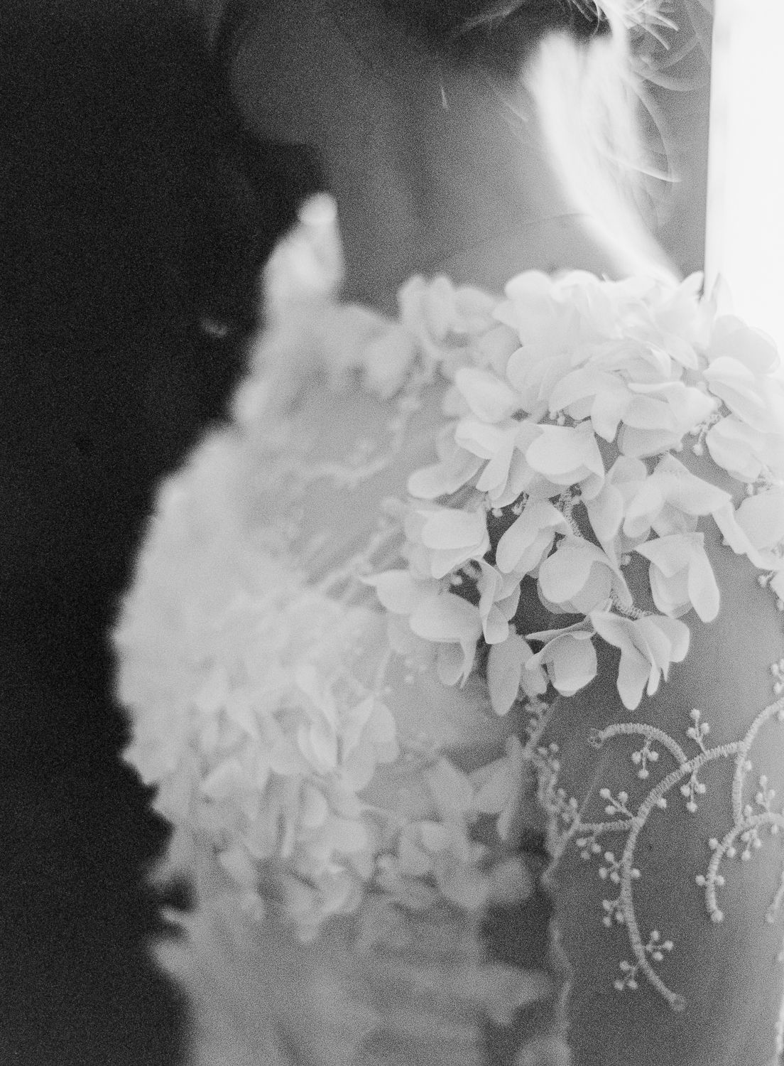 Gros plan sur les détails complexes d'une application florale sur une élégante robe de mariée, photo en noir et blanc.