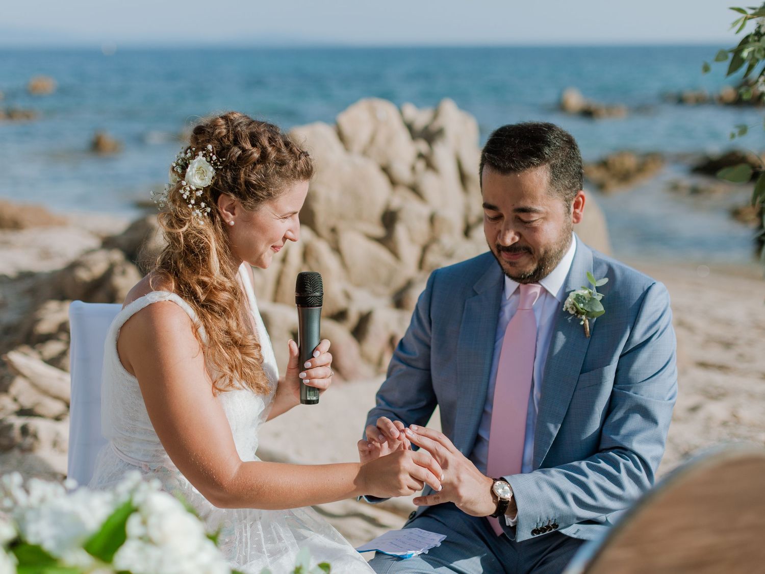 Les mariés échangent leurs alliances lors d'une cérémonie de mariage romantique en bord de mer, avec la mer bleue