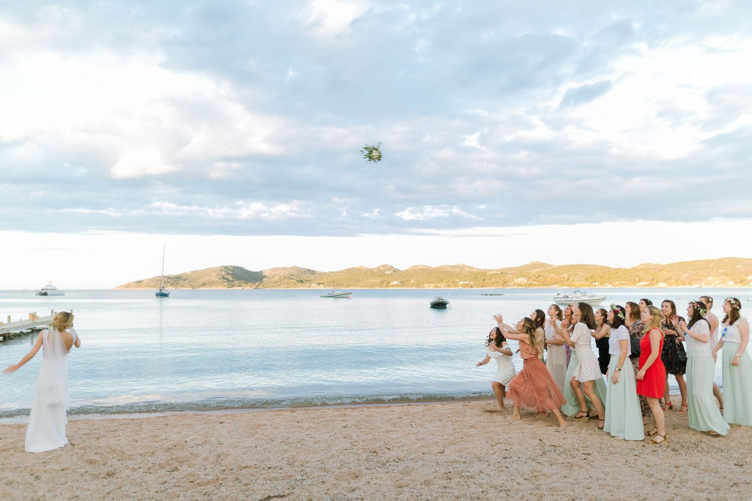 La mariée lance son bouquet à ses demoiselles d'honneur en robes colorées au maora Beach à Bonifacio