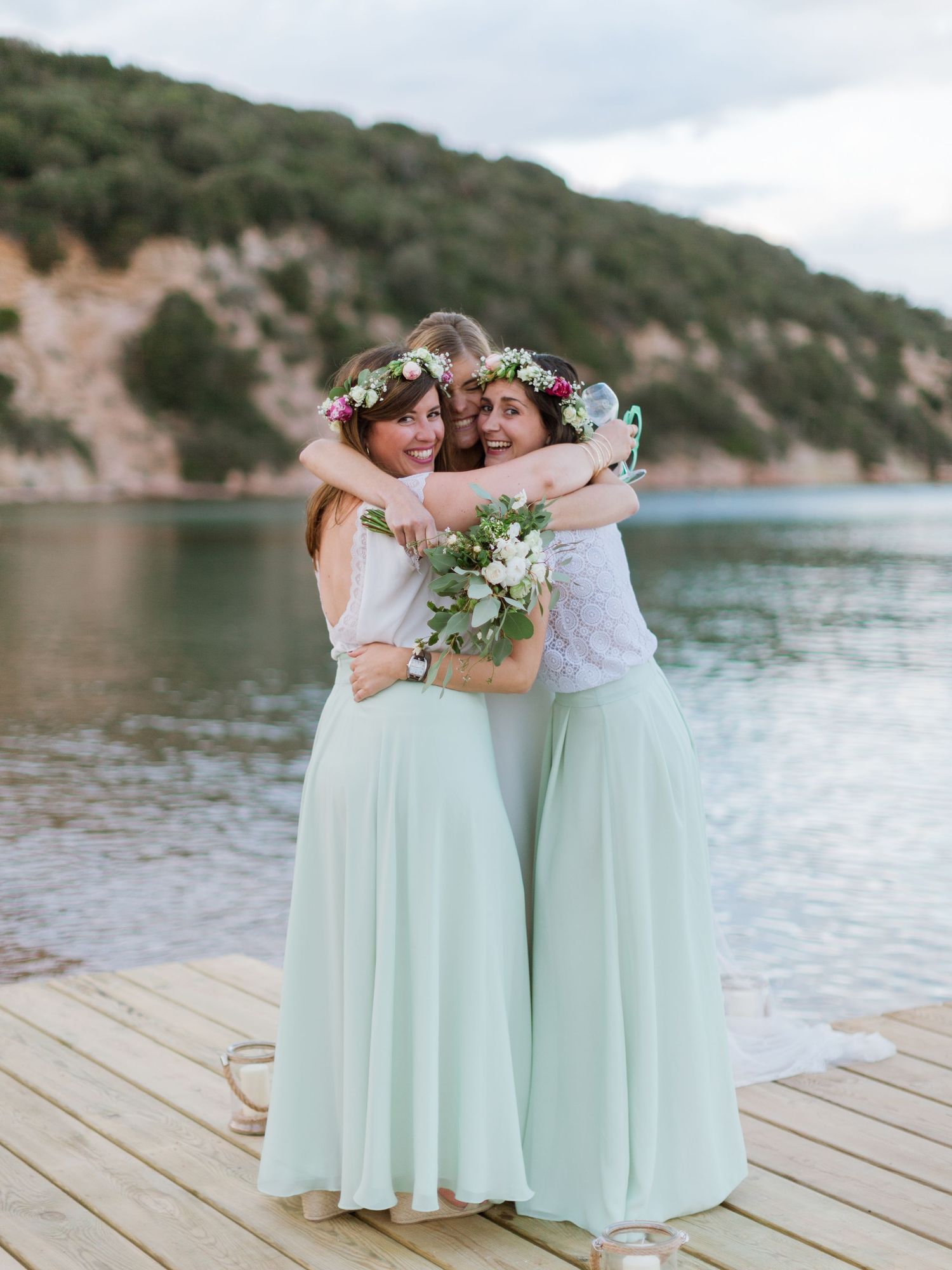 Trois demoiselles d'honneur en jupes vert menthe et couronnes de fleurs s'enlacent joyeusement en corse à Bonifacio