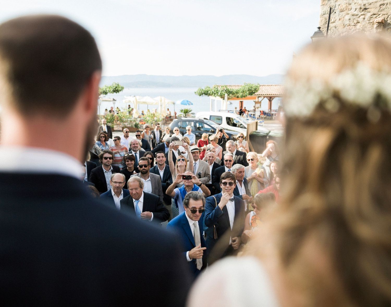 Les invités arrivant au lieu de la cérémonie en bord de mer, vus du point de vue des mariés à l'église de campomoro corse