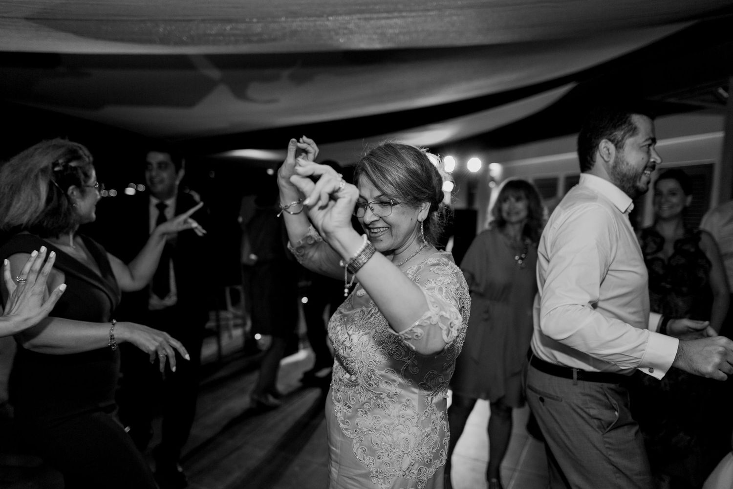 Photo en noir et blanc d'invités dansant joyeusement lors d'une réception de mariage.