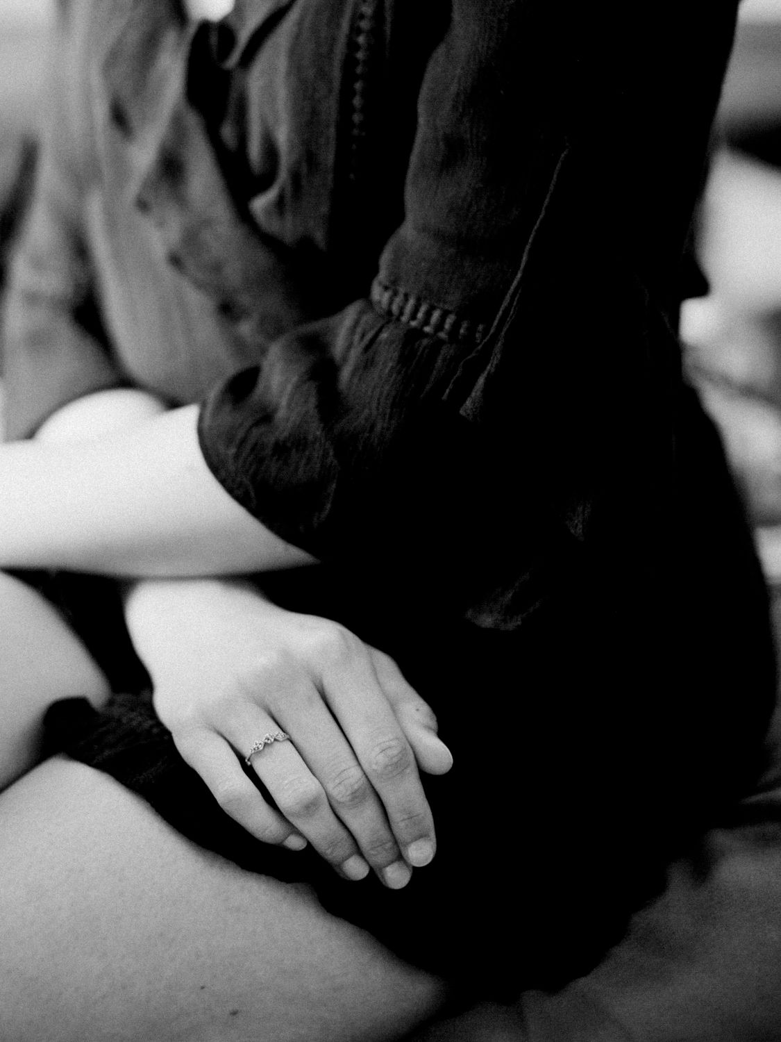 Gros plan en noir et blanc d'une main de femme ornée d'une délicate bague de fiançailles.