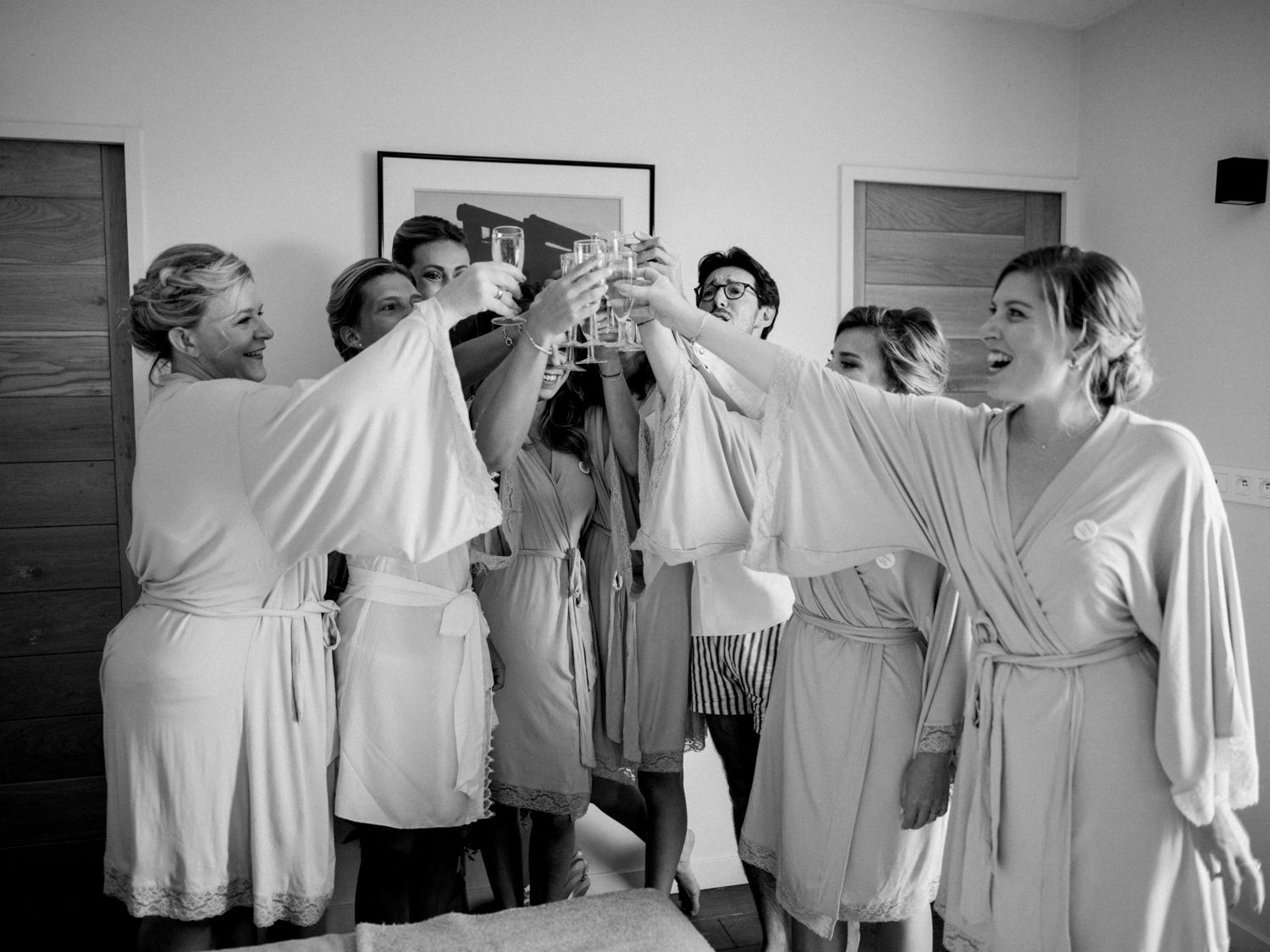 Les demoiselles d'honneur en robes blanches trinquent avec des coupes de champagne lors des préparatifs de la mariée.