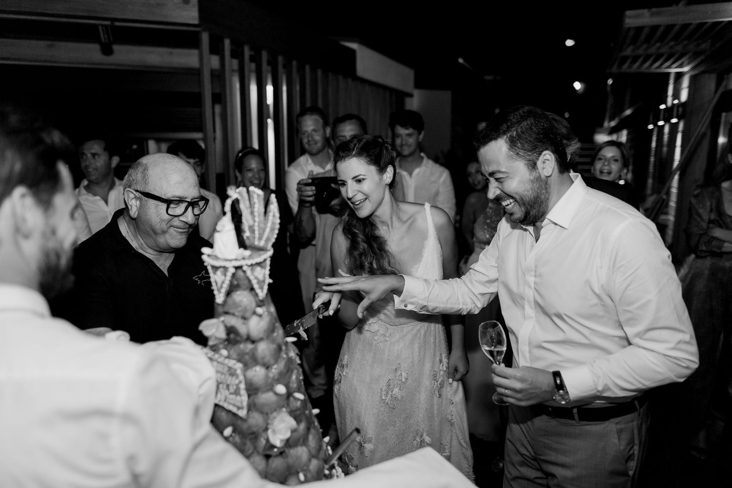 Photo en noir et blanc d'invités réunis autour d'une présentation de gâteaux décoratifs lors d'une soirée élégante.