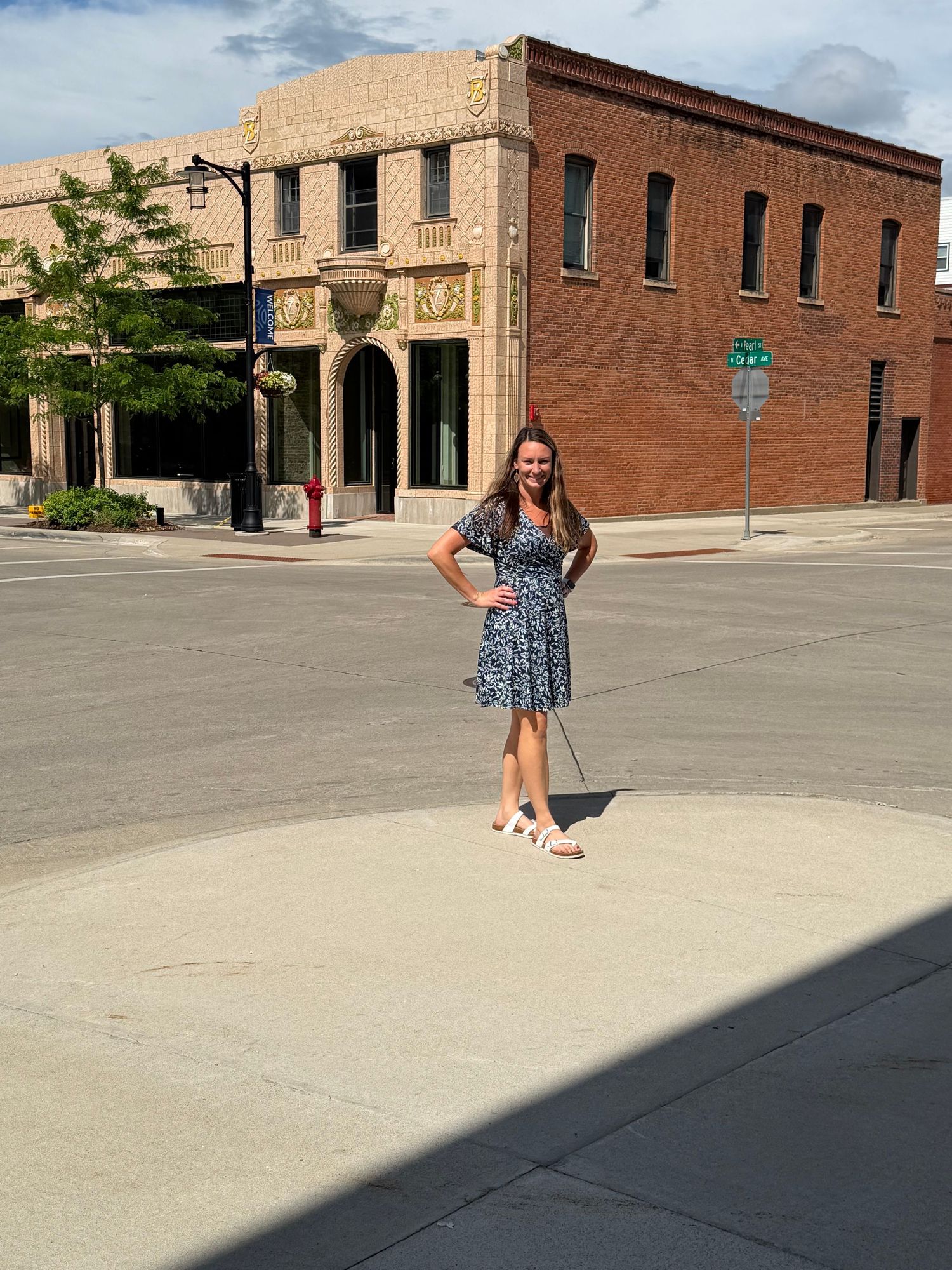 Morgan standing on a sunny street corner in Southern Minnesota, representing her warm and supportive creative services for small businesses.