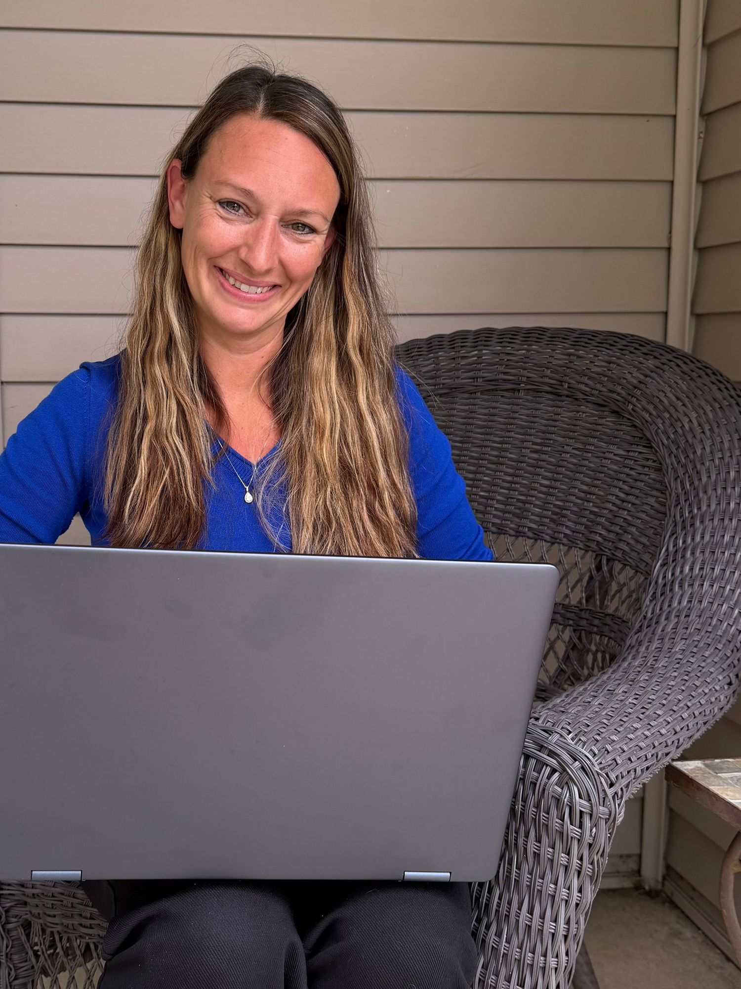 Morgan sitting on a porch with her laptop, representing the heart‑centered creative support she offers through Silver Lining Marketing.