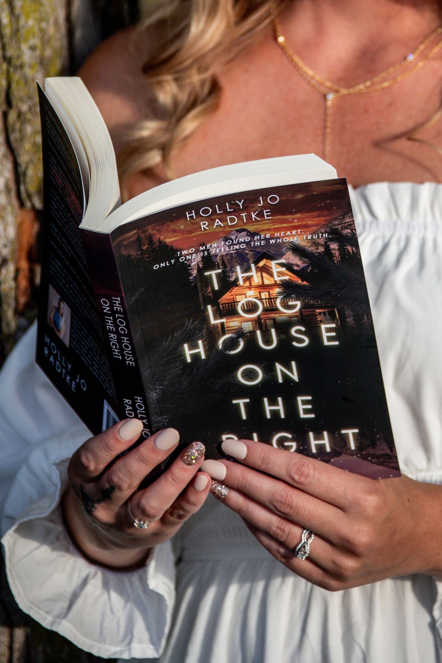 Close-up of hands holding The Log House on the Right by Holly Jo Radtke with decorated nails.