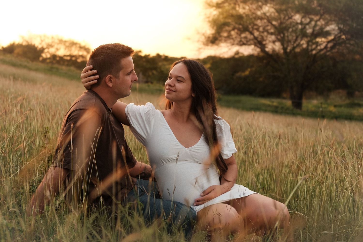 Couple attendant un bébé dans un champ au coucher du soleil – séance photo grossesse naturelle en Nouvelle-Calédonie par Solène Photographie