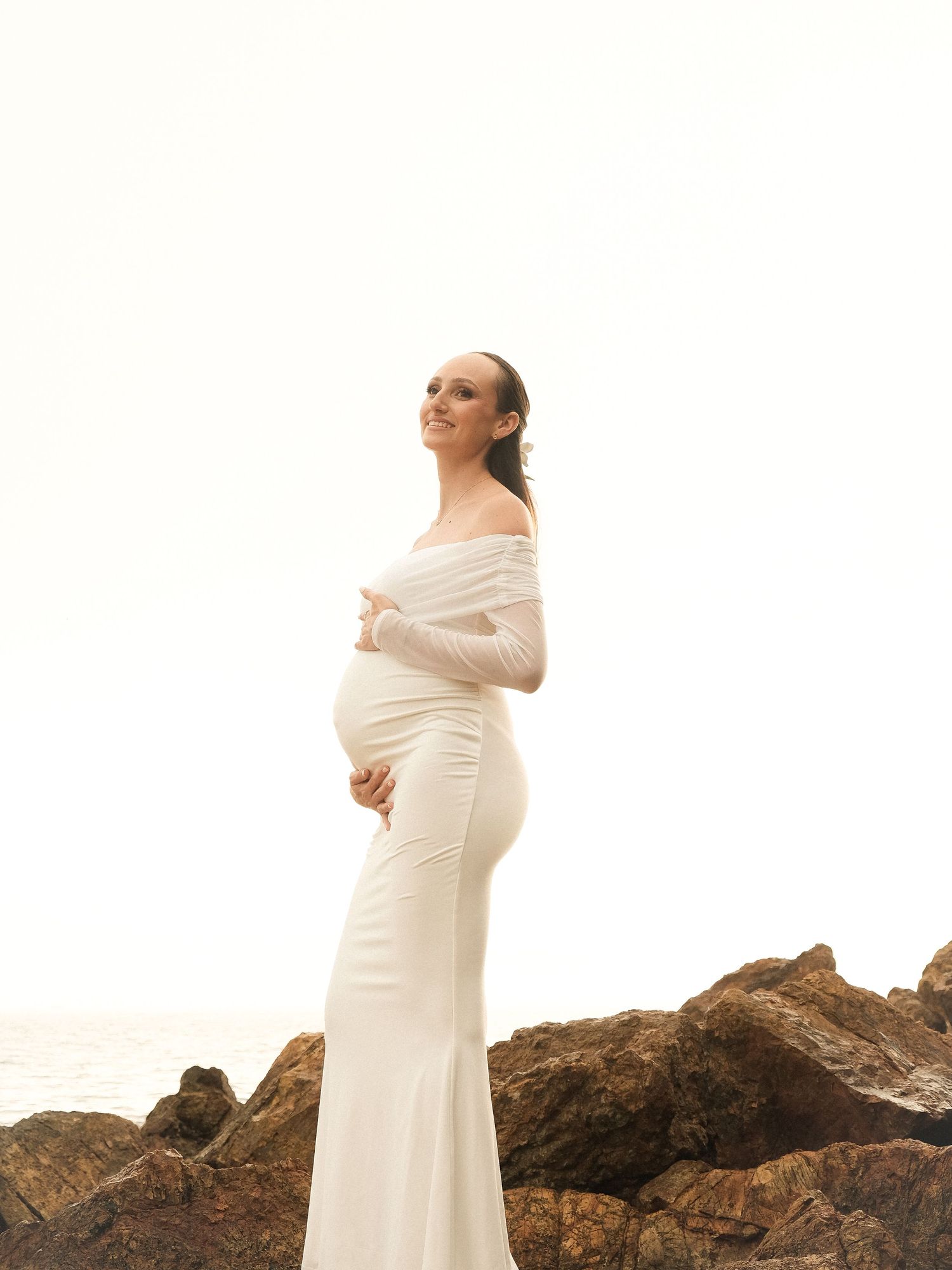 Future maman en robe blanche sur les rochers – shooting grossesse élégant en Nouvelle-Calédonie par Solène Photographie