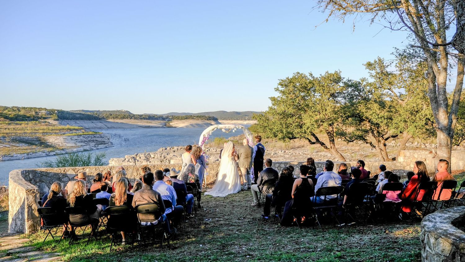A wedding ceremony with wedding guests on a lake in Texas.