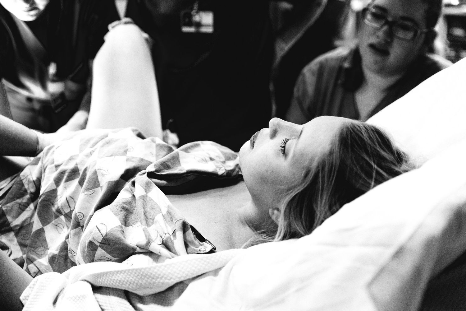 Woman in labor lying on hospital bed during childbirth in delivery room.