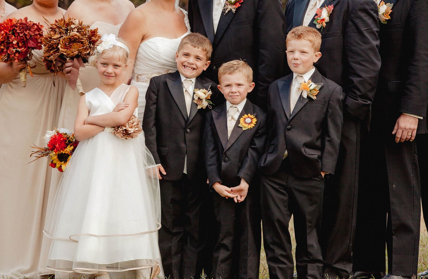 Children dressed in formal wedding attire, including flower girl in white dress and ring bearers in black suits with boutonnieres.