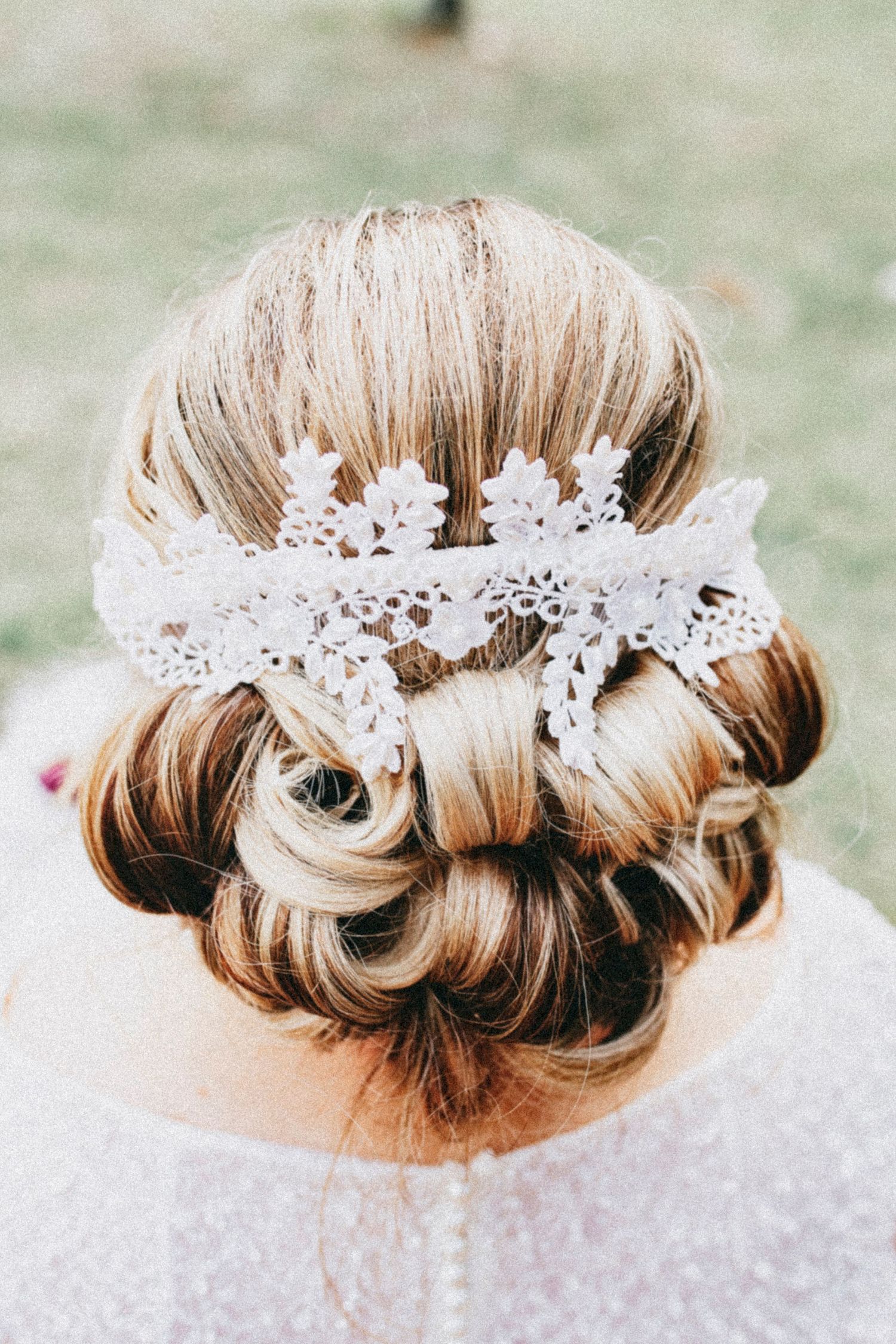 Elegant bridal updo with lace hair accessory, showcasing a romantic low bun hairstyle for weddings.