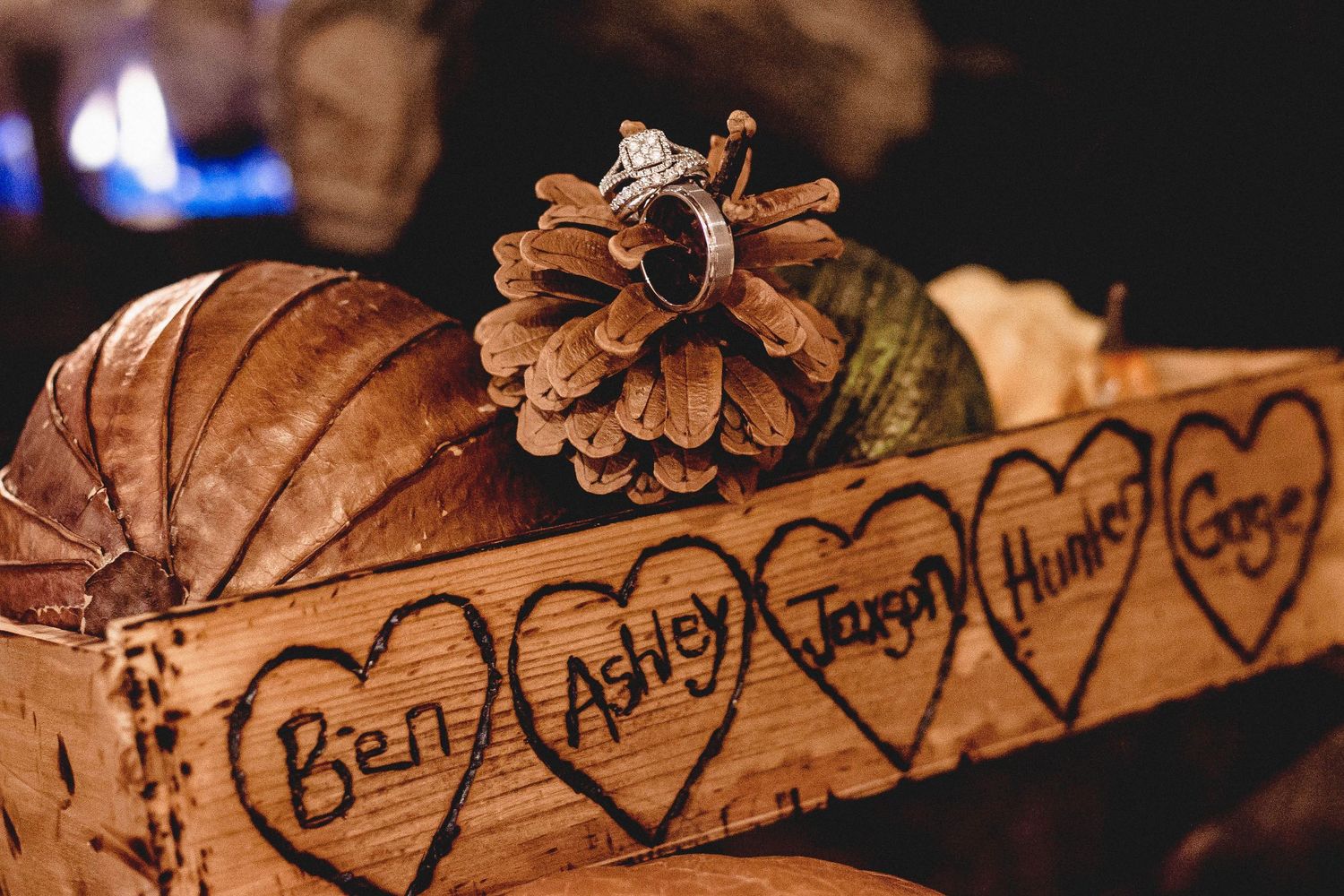 Rustic wooden box with carved heart names Ben, Ashley, Jason, Hunts, Gaye, pine cone, and diamond ring at fall wedding.
