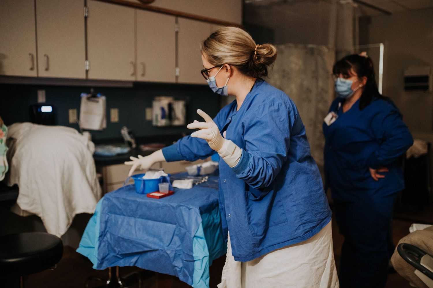 Medical nurse in blue scrubs preparing surgical instruments in a hospital procedure room.