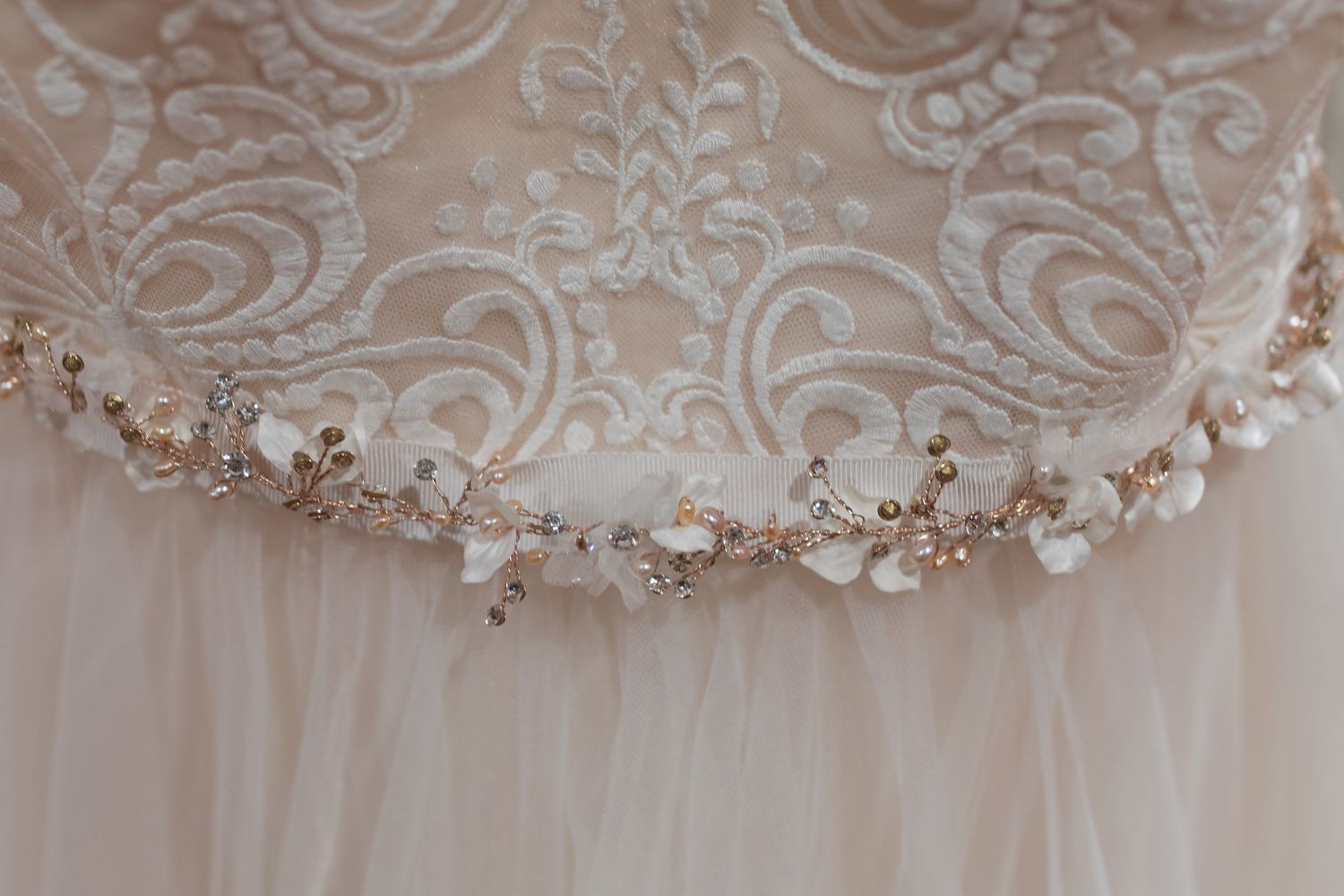Close-up of an elegant bridal gown featuring intricate lace bodice and delicate floral crystal embellished waistband.