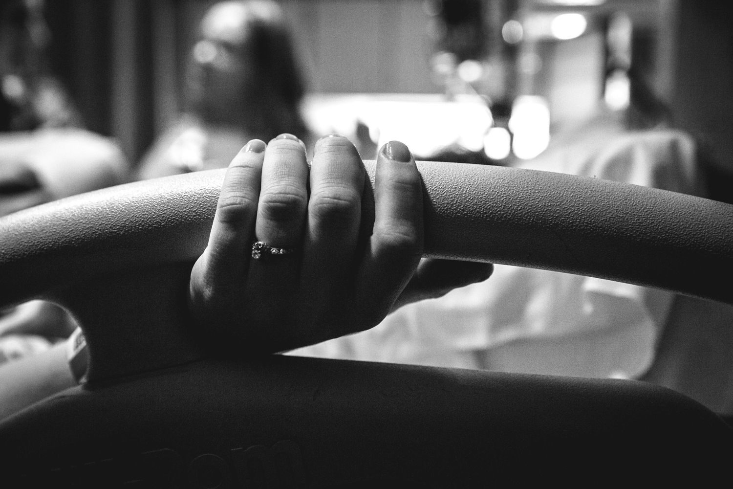 Close-up of woman's hand with diamond ring gripping hospital bed rail during labor.