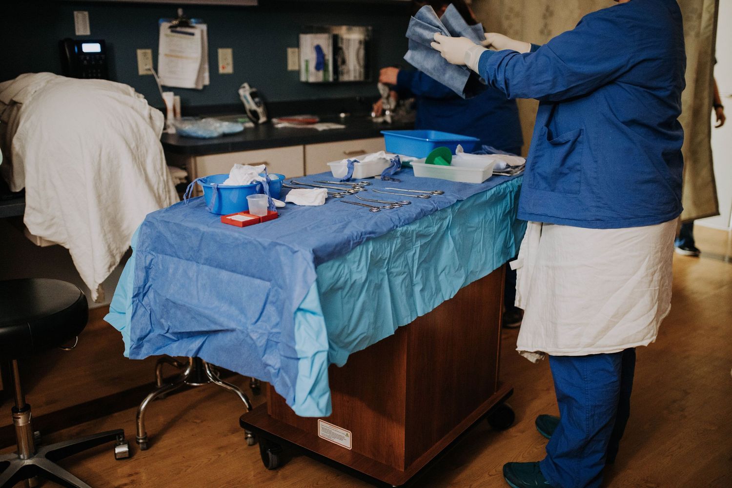 Healthcare professional in blue scrubs organizing medical supplies on a sterile surgical tray.