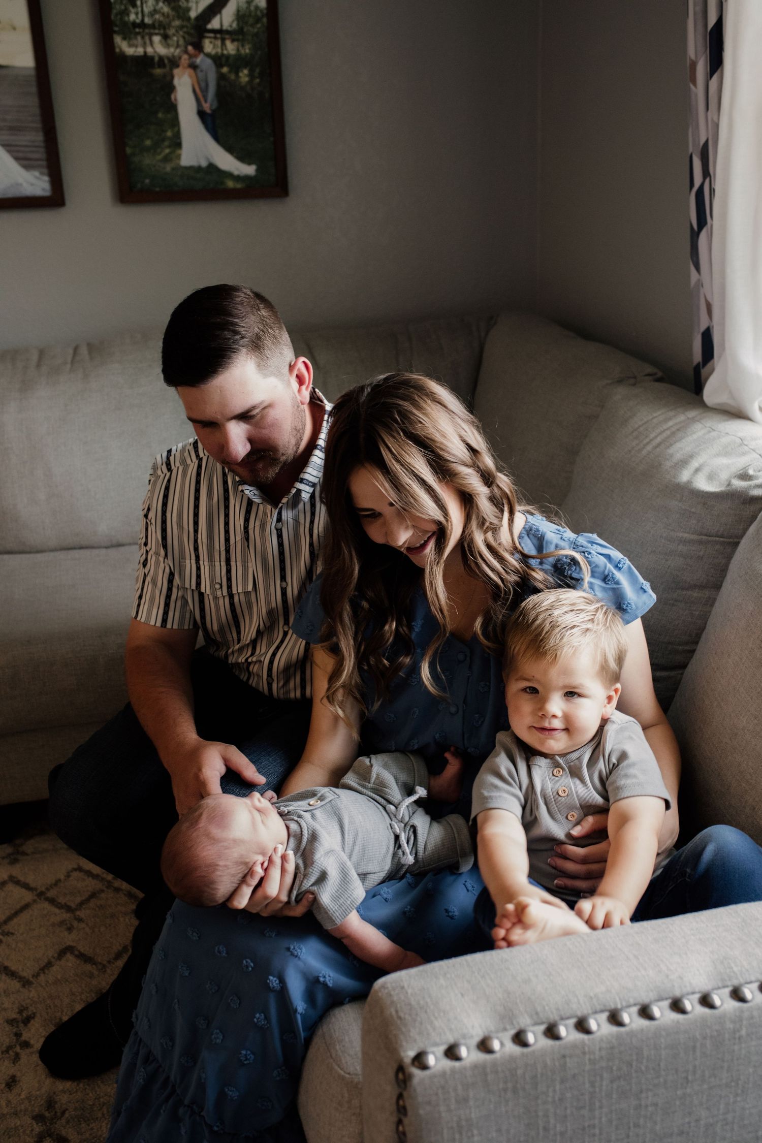 Happy young family with parents and toddler son sitting on floor together with newborn baby.